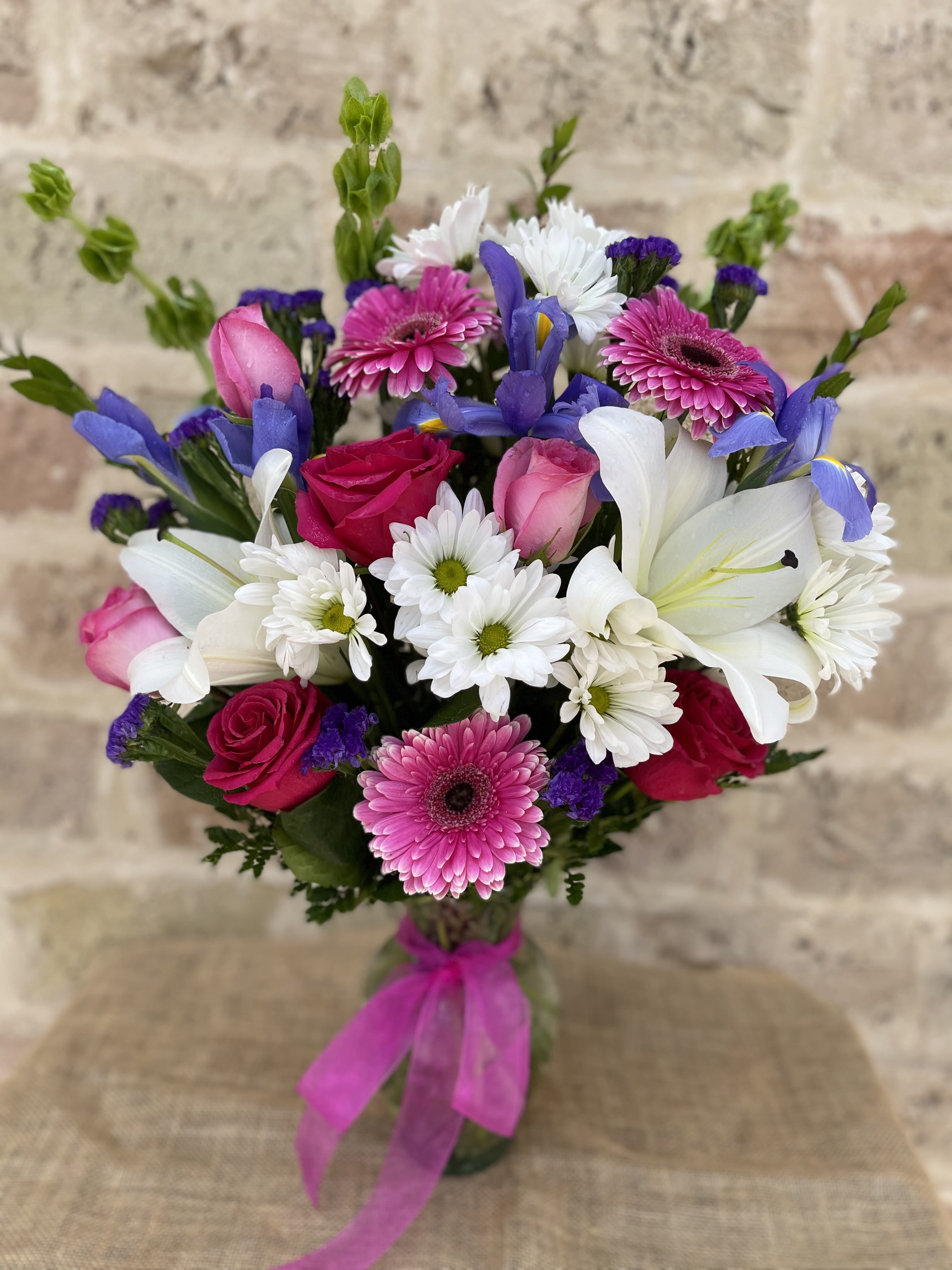 Bouquet of pink roses, white lilies, and daisies with purple accents