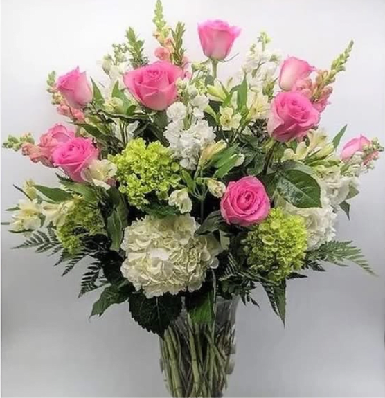Bouquet of pink roses, white hydrangeas, and white flowers in a clear vase