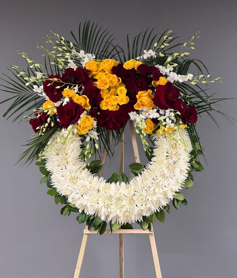 Standing floral wreath with red and yellow roses on an easel