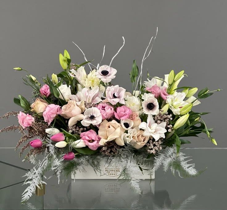 Pink and white floral arrangement in a white box with lilies and roses