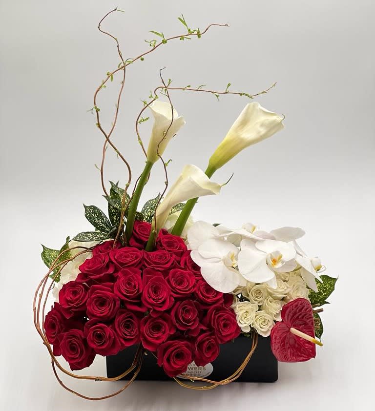 Red roses with white calla lilies and orchids in a black container