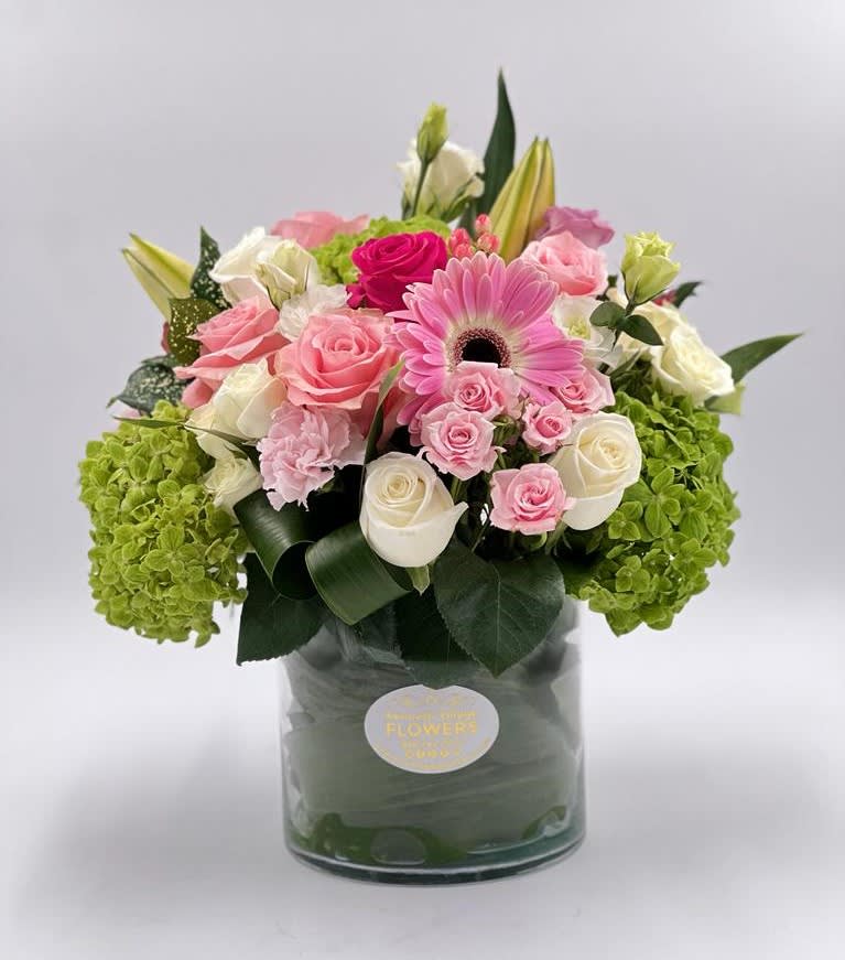 Pink and white roses with a pink gerbera daisy in a glass vase