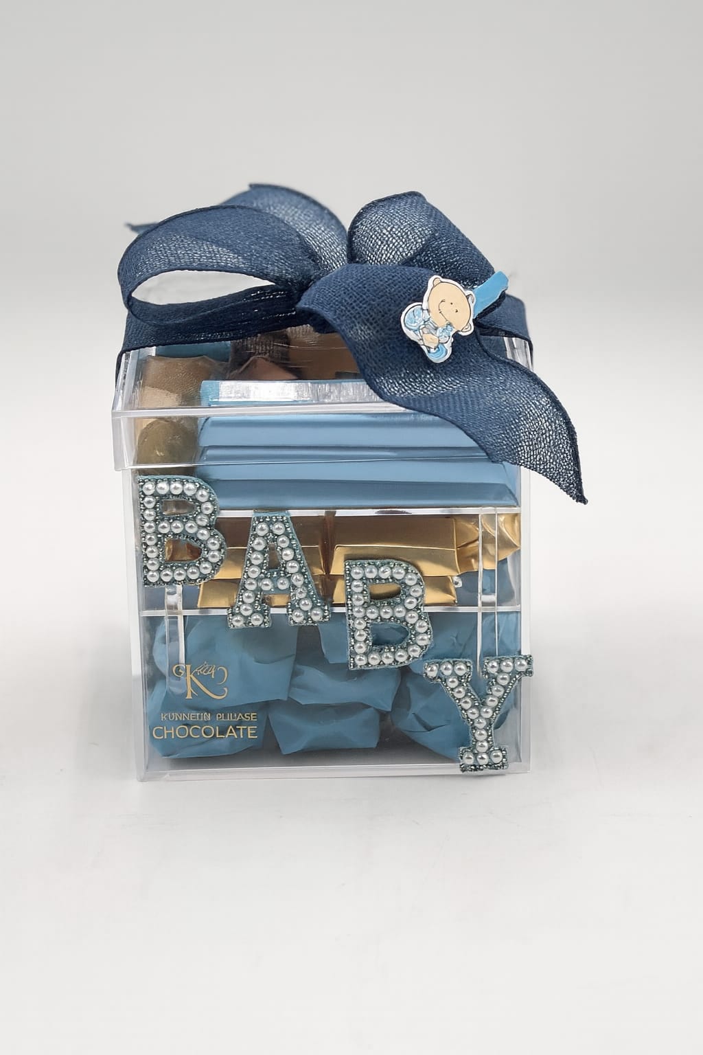 Clear gift box with blue ribbon and chocolate pieces labeled BABY