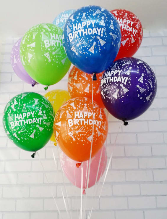 Cluster of colorful birthday balloons against a white brick wall