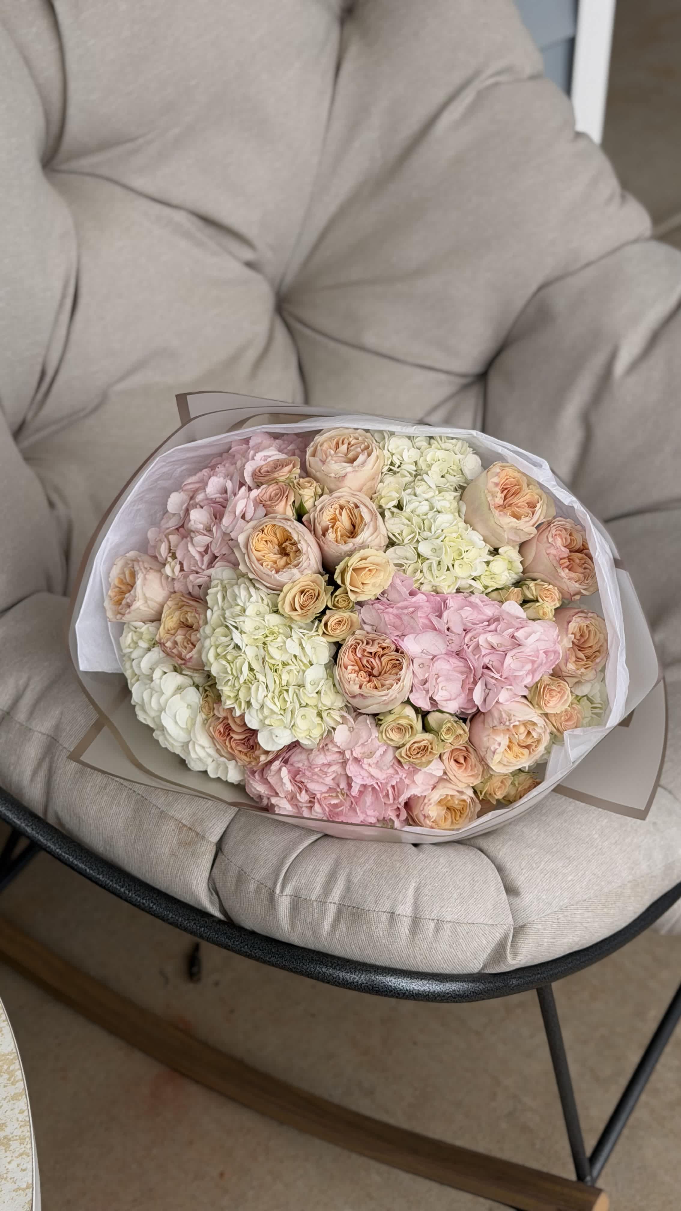 Bouquet of pastel roses and hydrangeas wrapped in white paper