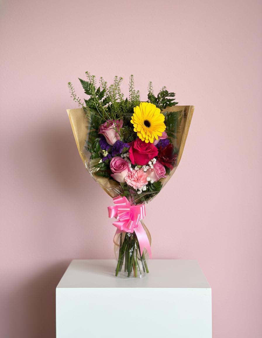 Mixed bouquet with pink and yellow flowers wrapped in clear paper