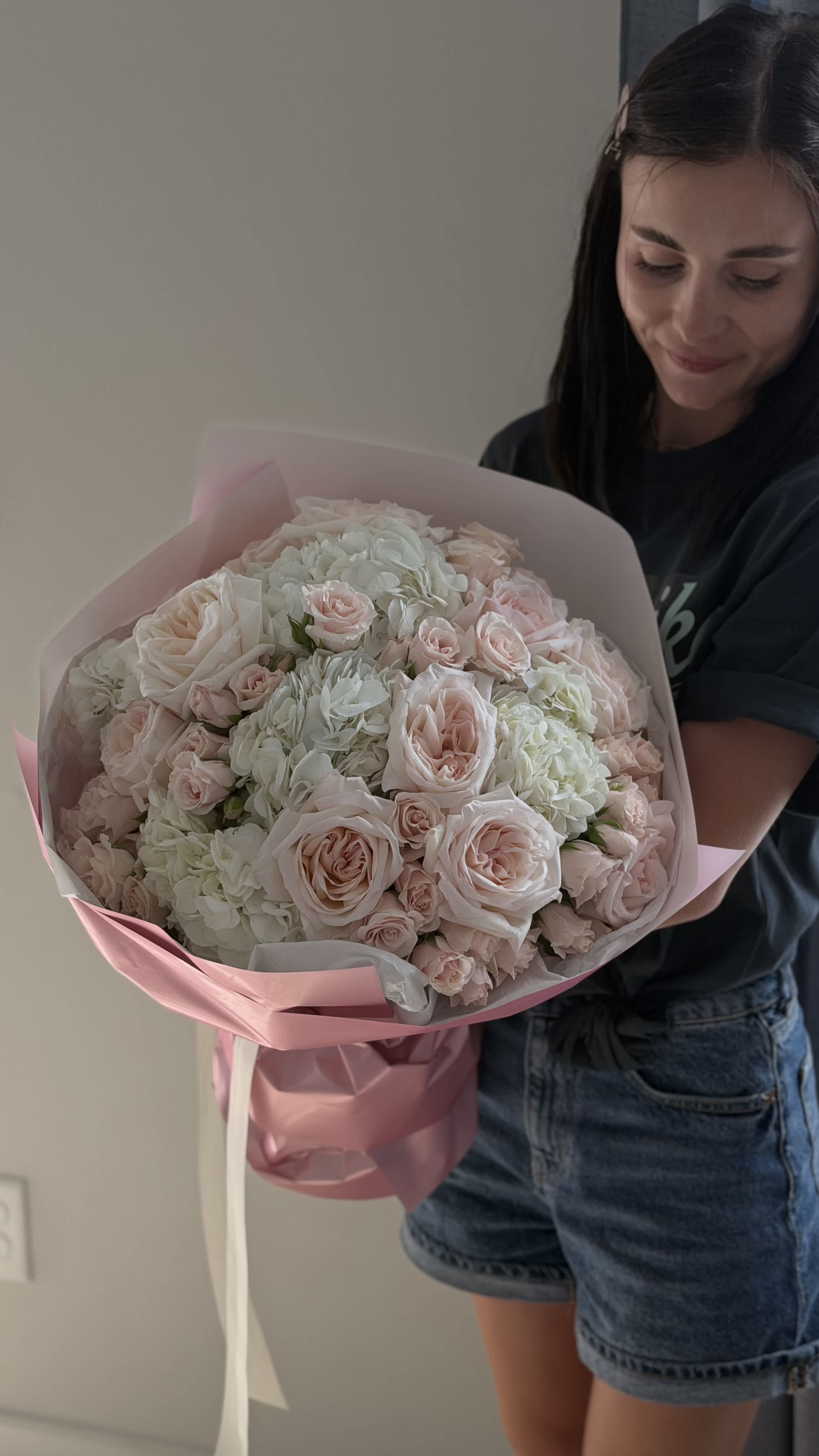 Large bouquet of pale pink roses and white hydrangeas wrapped in pink paper