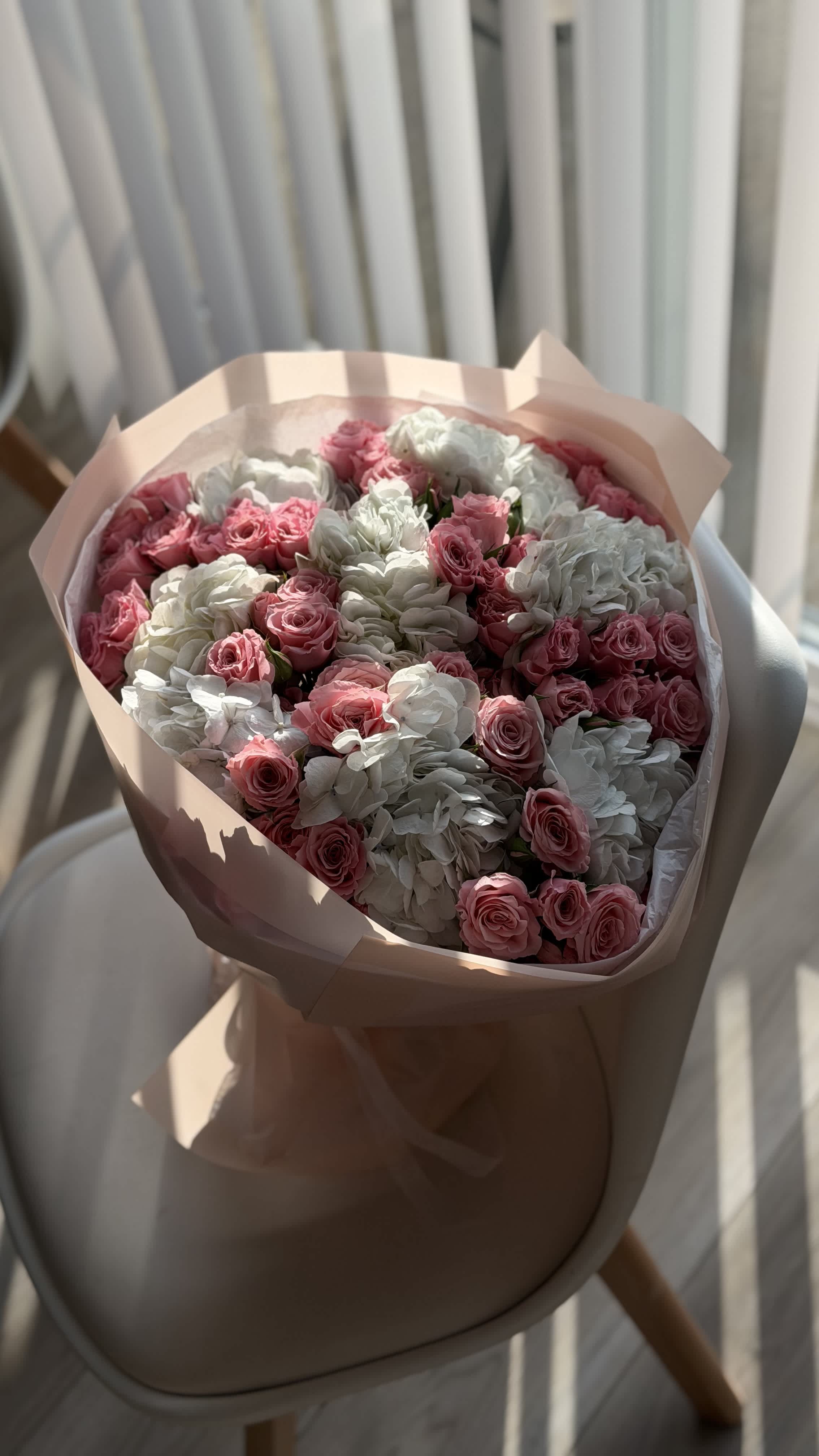 Bouquet of pink roses and white hydrangeas wrapped in pale pink paper