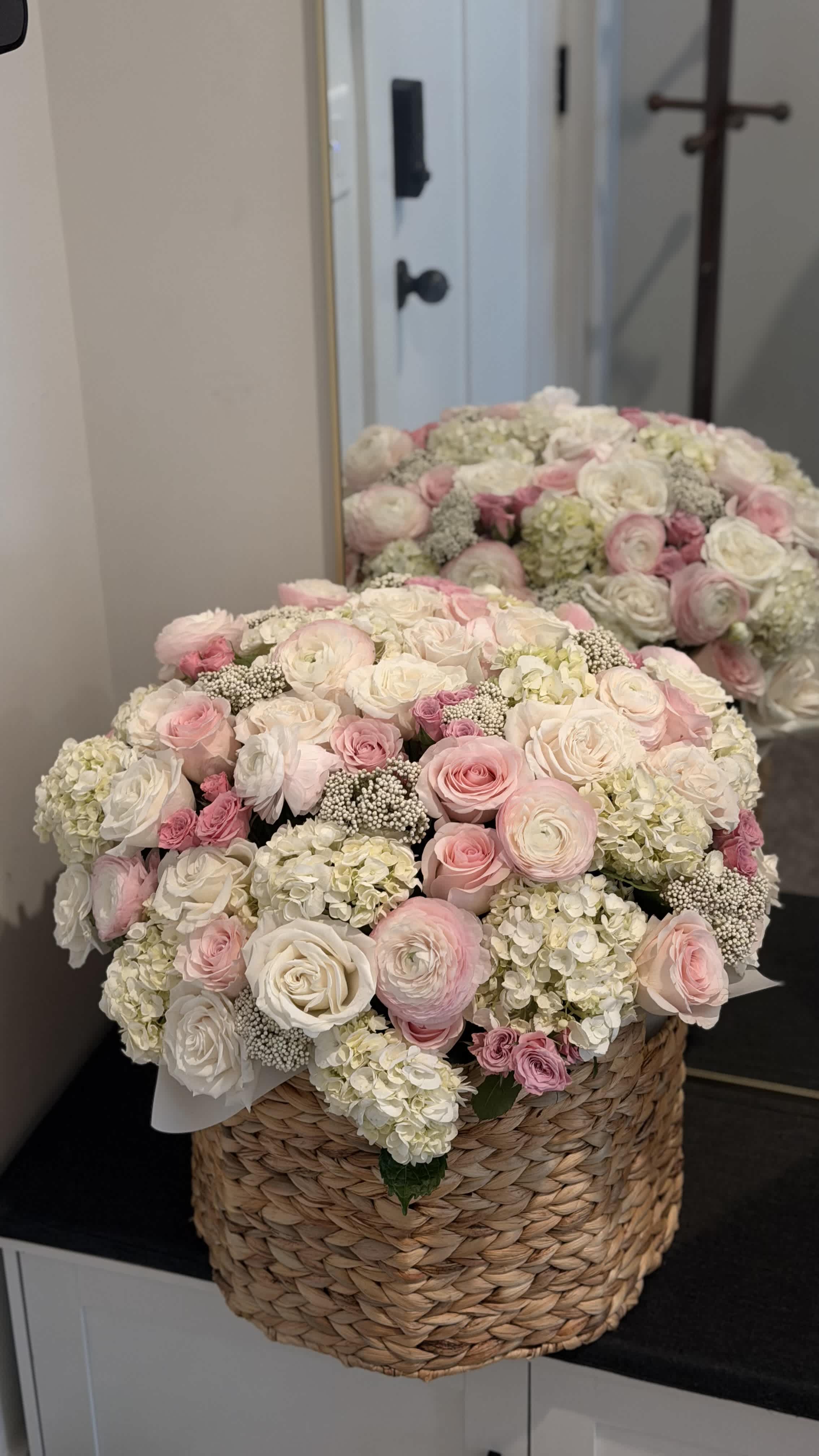 Large pink and white rose arrangement in a woven basket