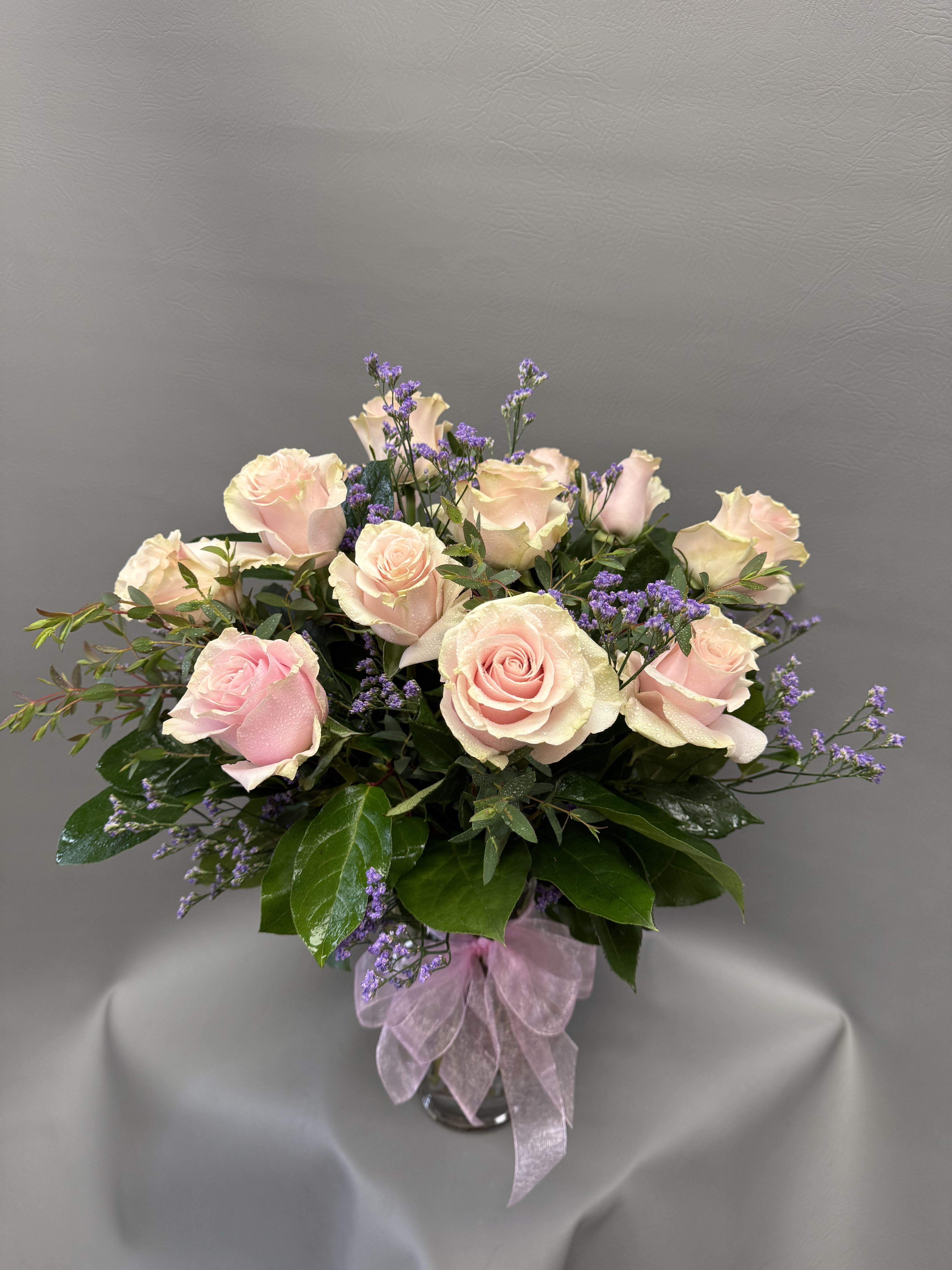 Light Pink Roses - Roses are always appropriate and who doesn't love pink! 1 dz carefully arranged in a classic glass vase with seasonal filler and greens. 