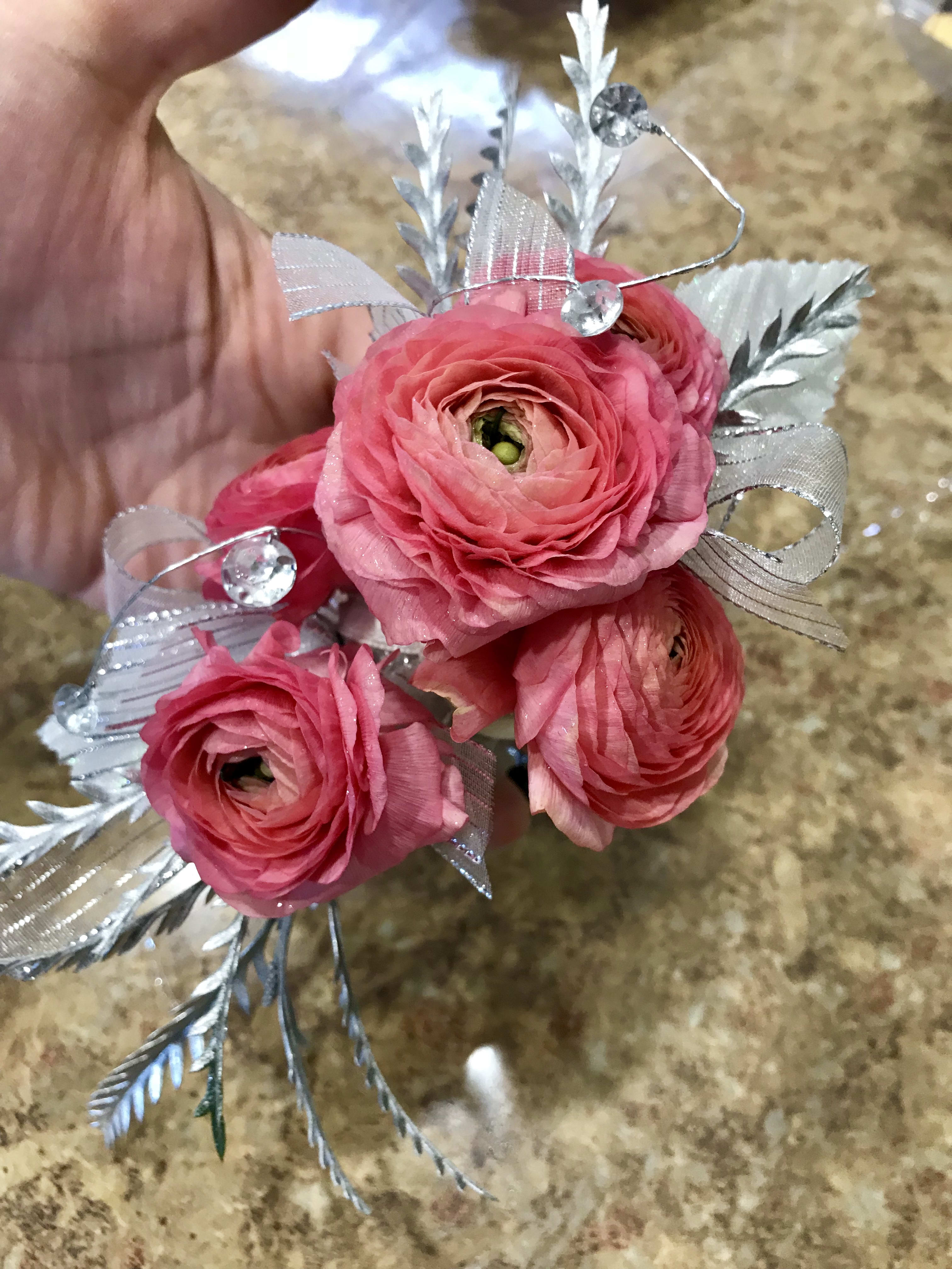 Small pink ranunculus bouquet with silver ribbon and decorative accents
