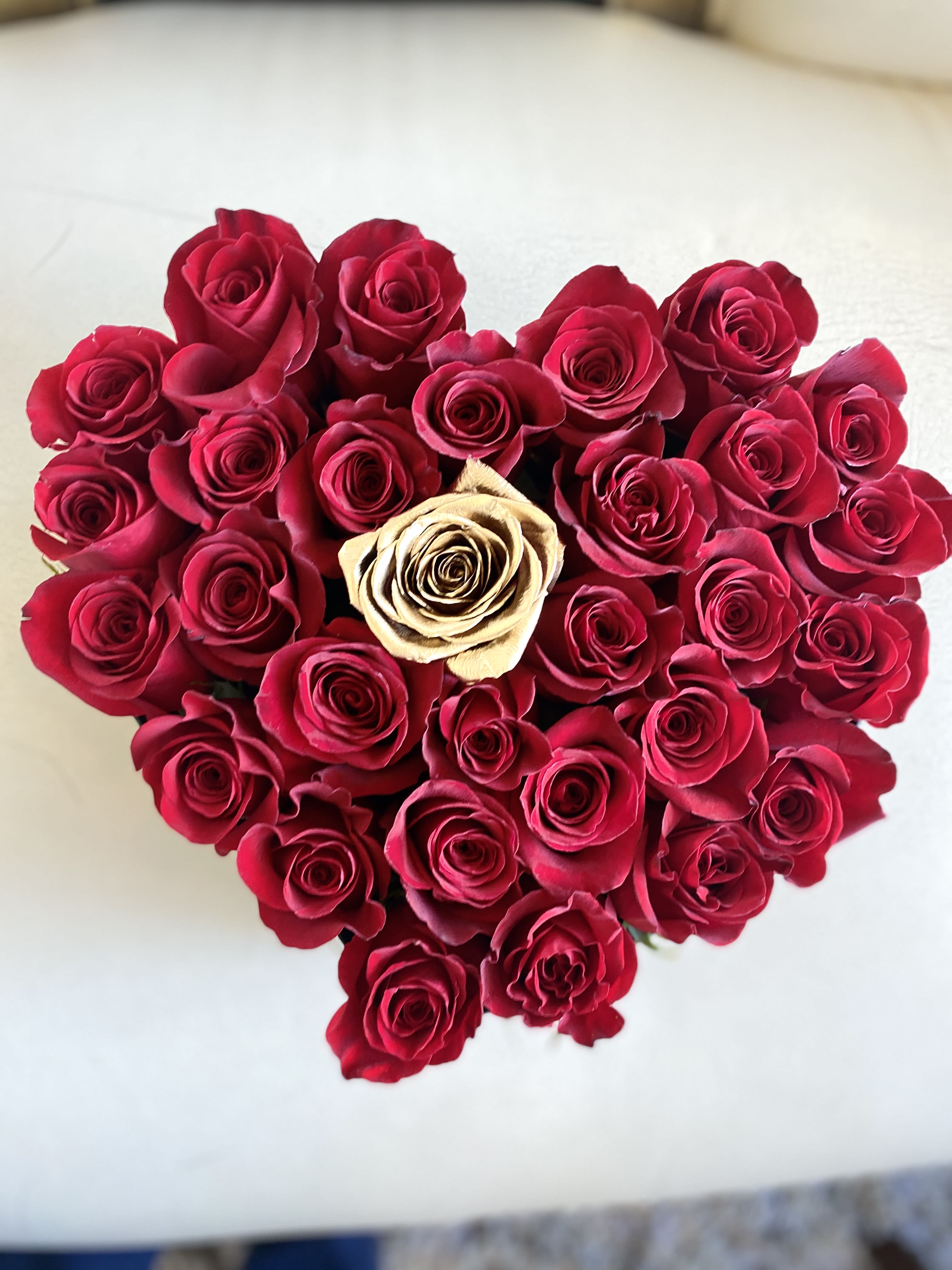 Heart-shaped bouquet of red roses with one cream rose in the center