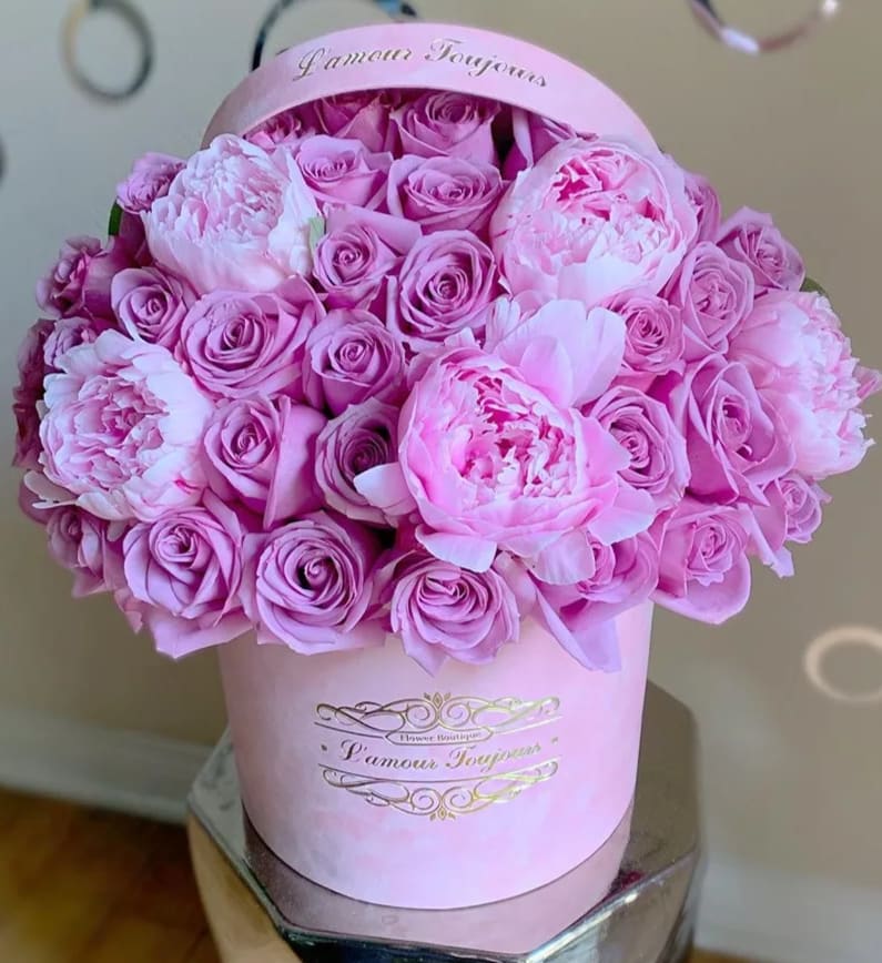 Pink roses and peonies arranged in a round pink hat box