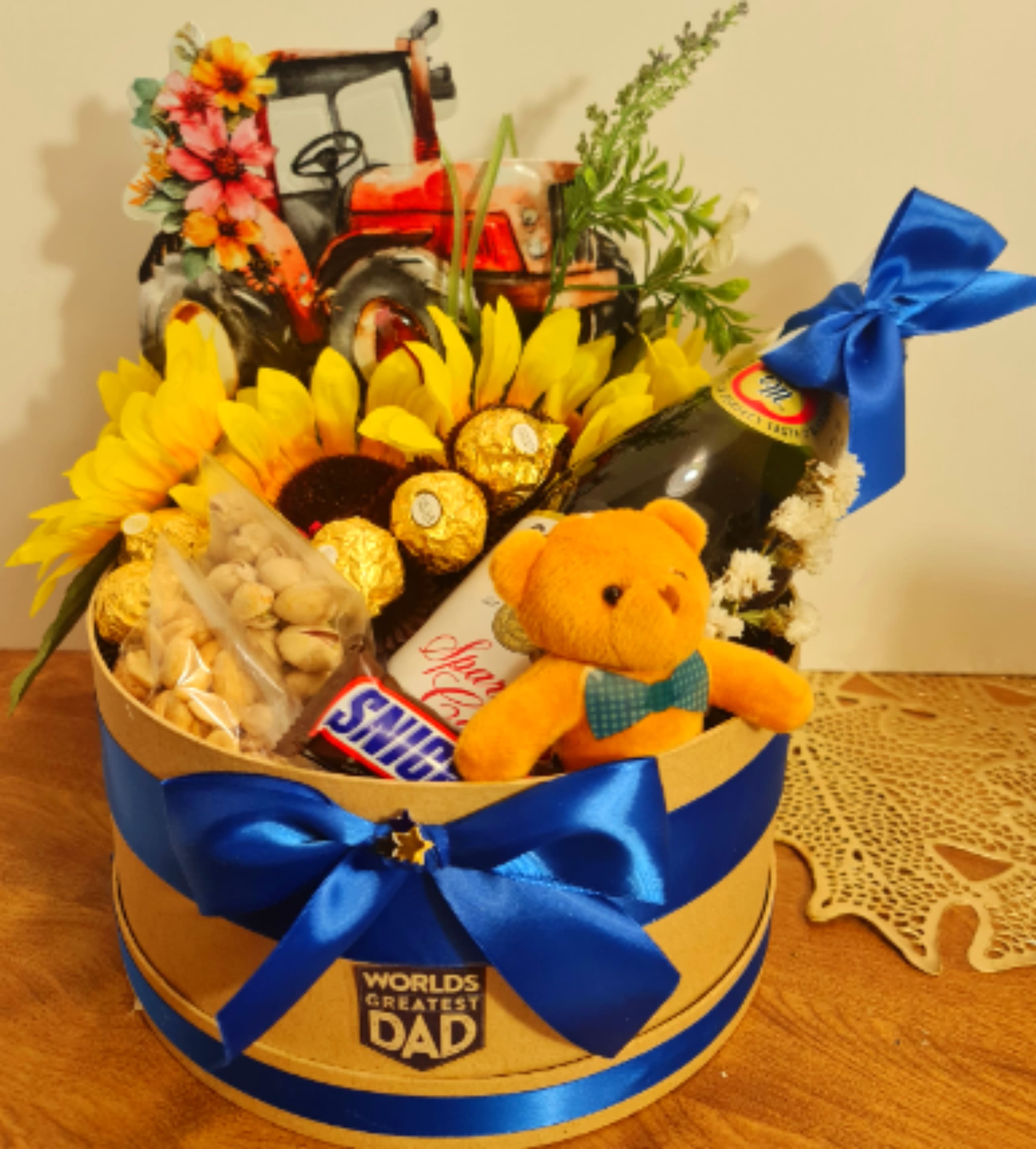 "World's Greatest Dad" Sunflower &amp; Tractor Gift Box - A charming gift box featuring a tractor-themed topper, bright sunflowers, Ferrero Rocher chocolates, premium snacks, a celebratory beverage, and an adorable teddy bear.
