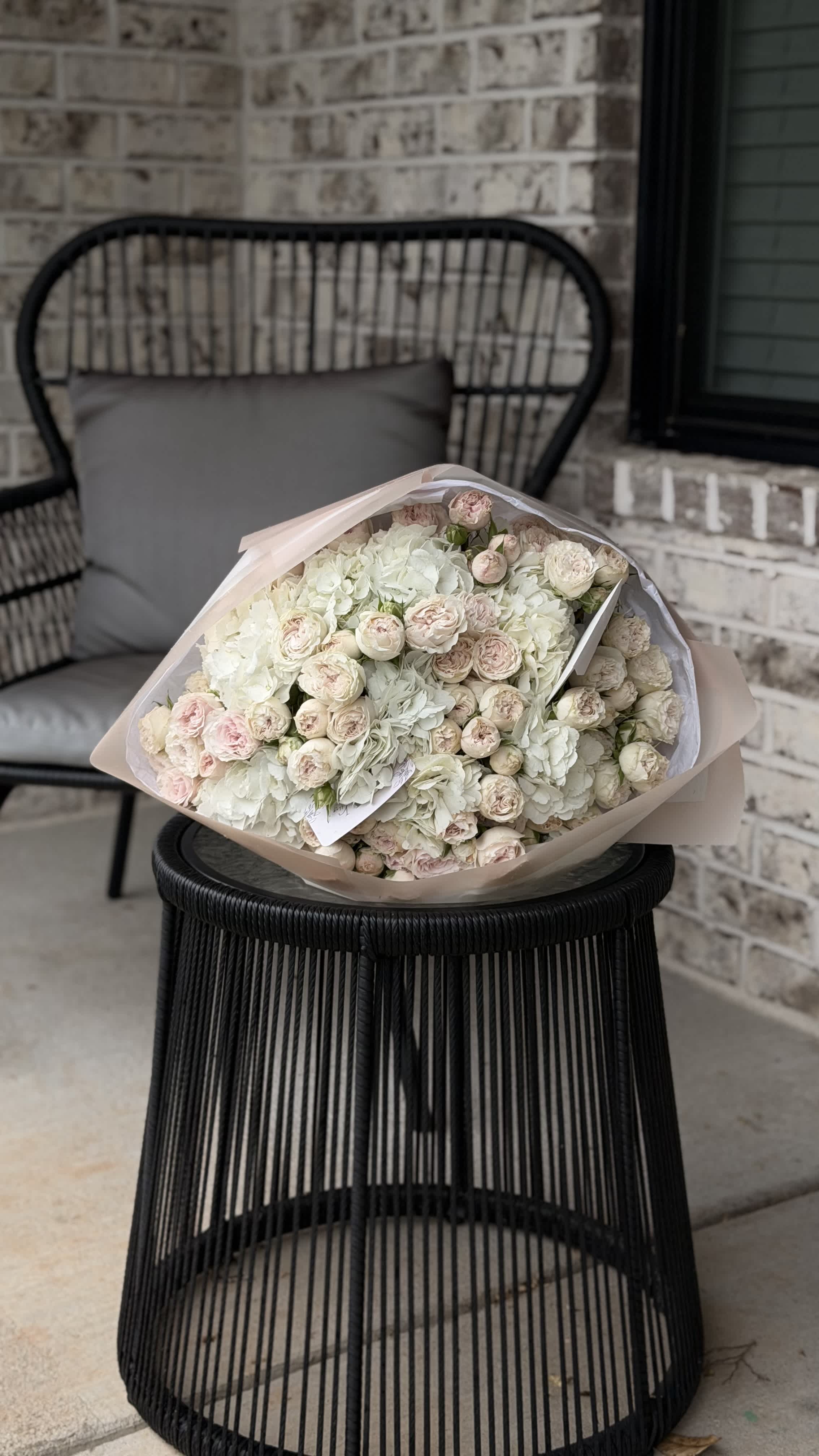 Large bouquet of pale pink and white roses wrapped in blush paper