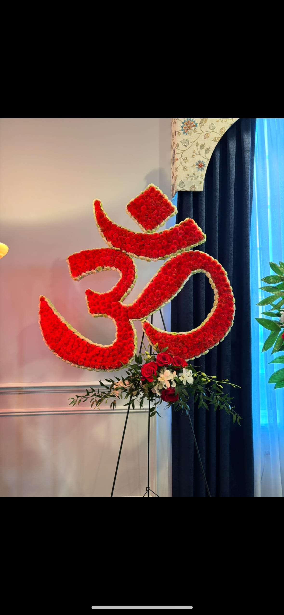 Large red floral Om symbol on a stand with roses at the base