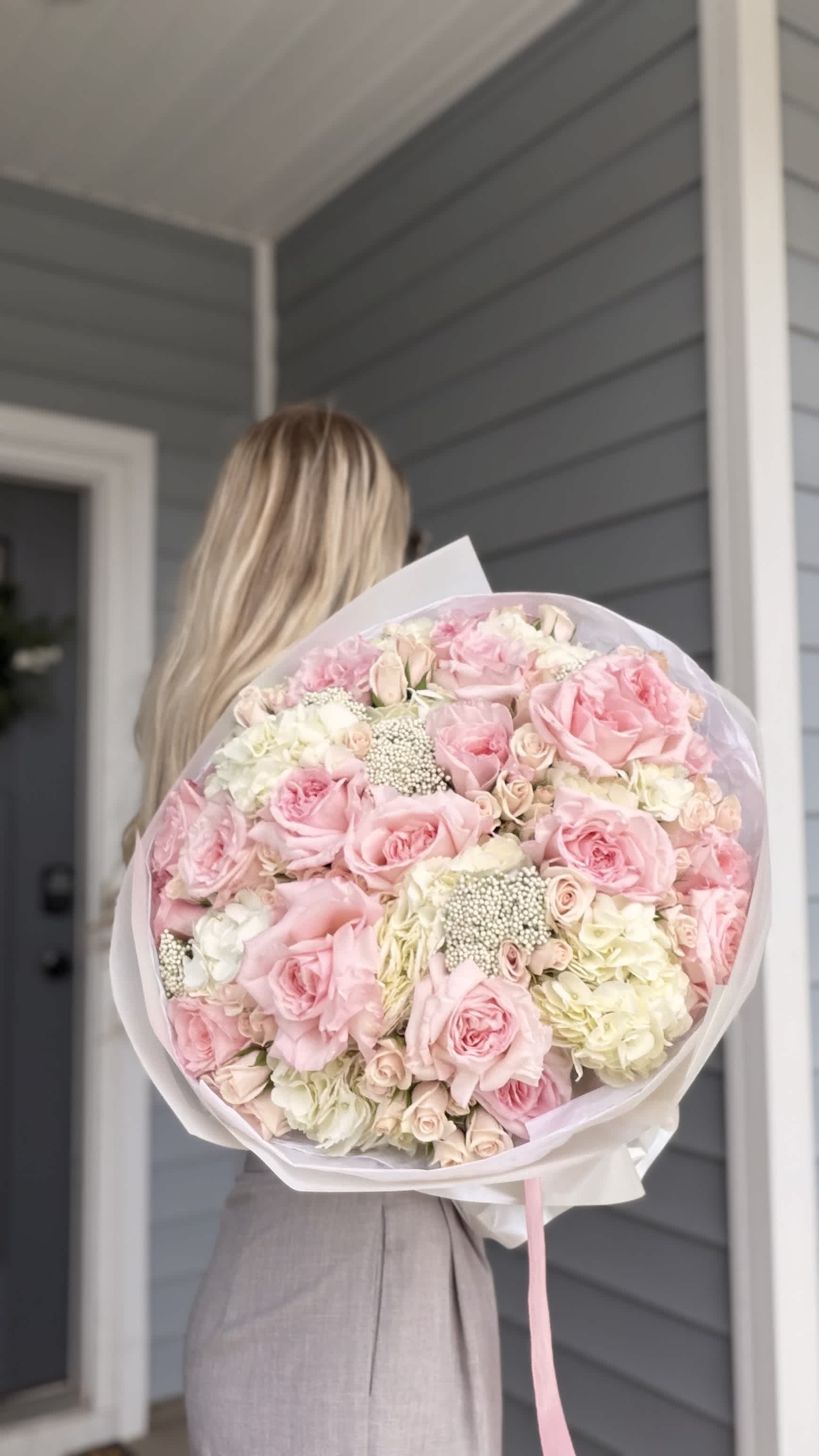 Large bouquet of pink and white roses wrapped in pale paper