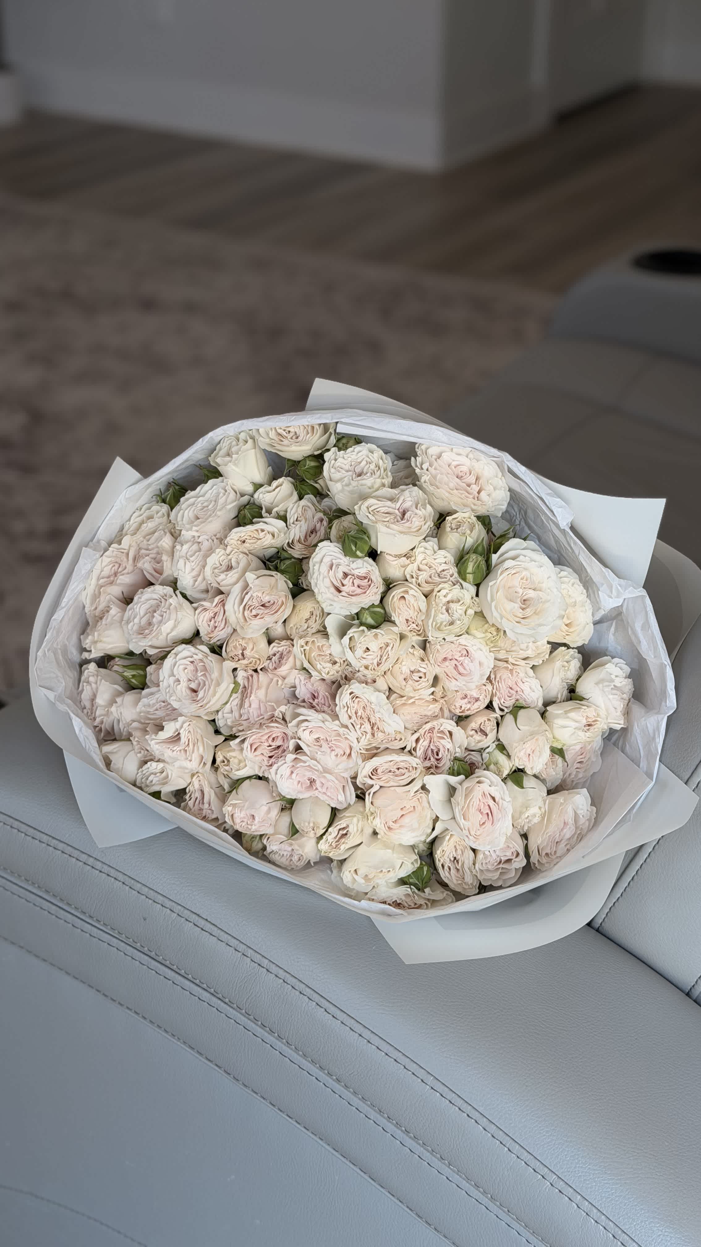 Bouquet of pale pink and white roses wrapped in white paper
