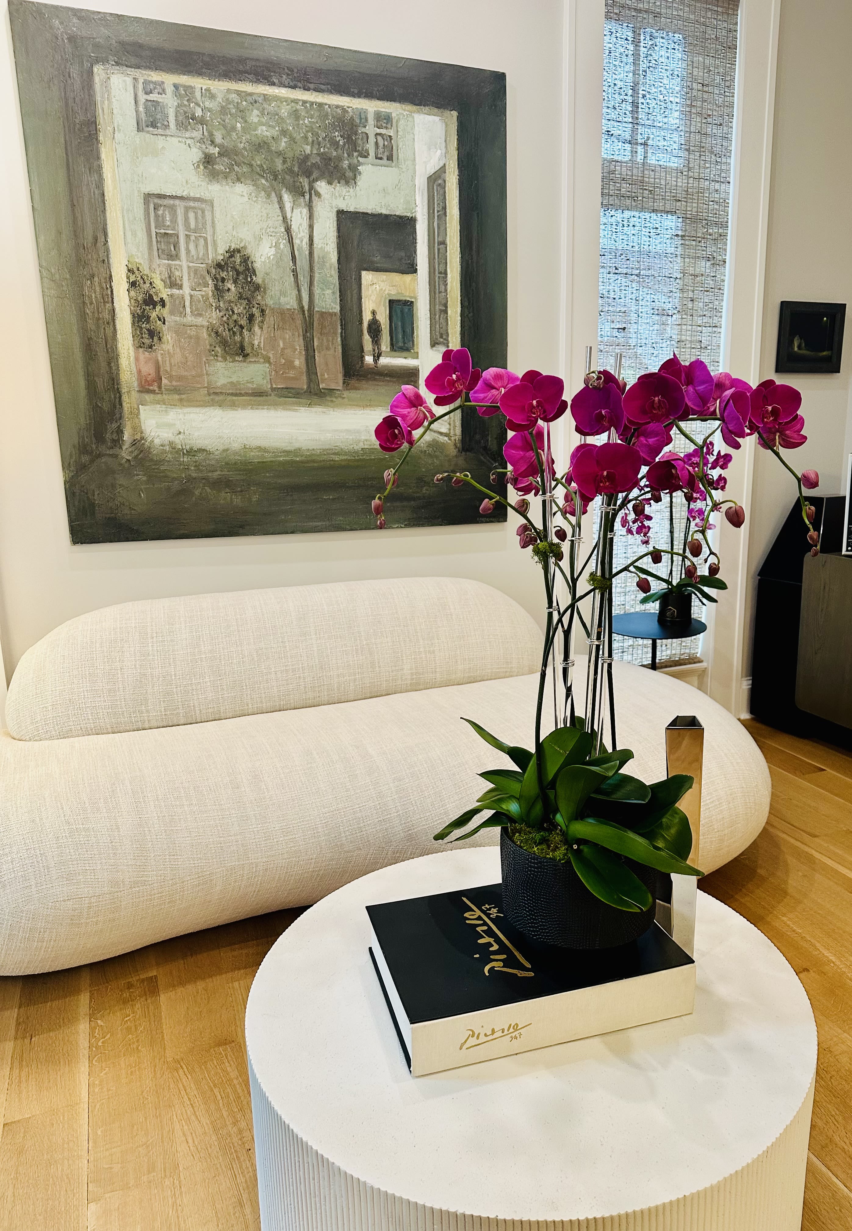 Pink orchids in a black pot on a white table