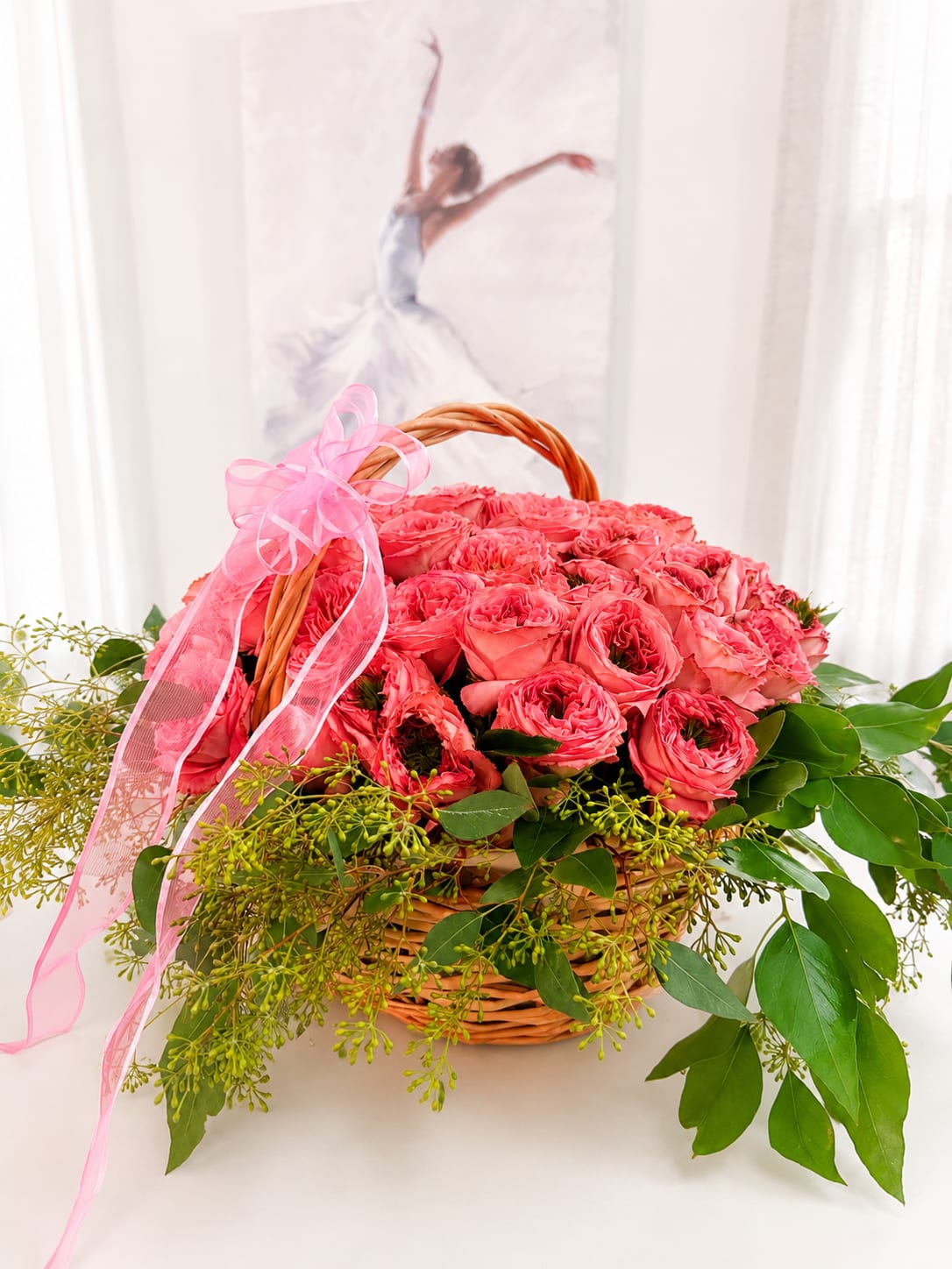 Pink roses in a wicker basket with a pink ribbon