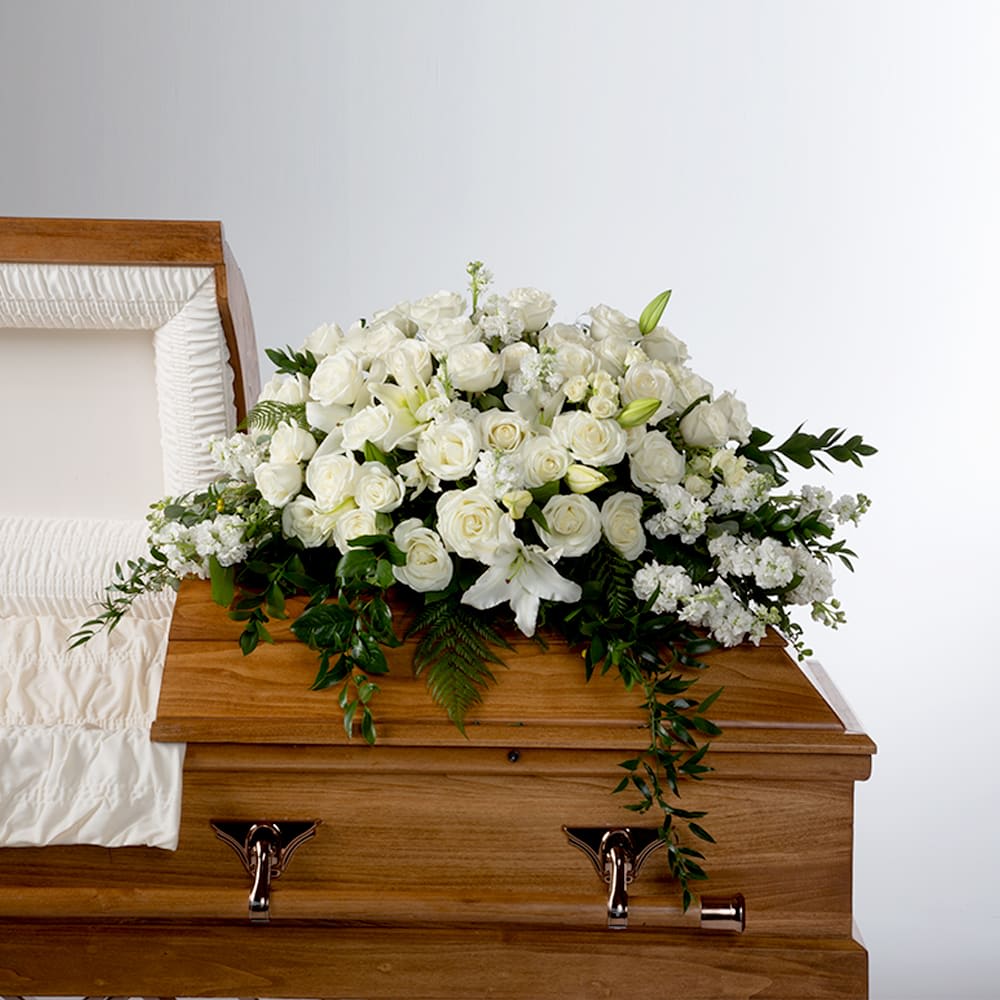 White floral casket spray on a wooden coffin