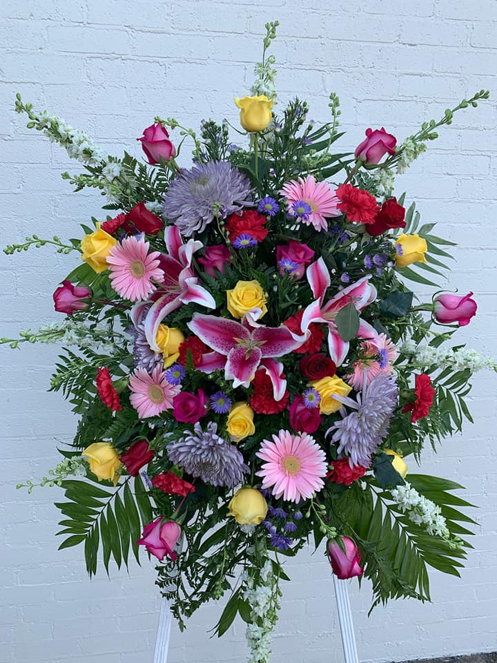 Large standing floral spray with pink, yellow, red, and lavender flowers