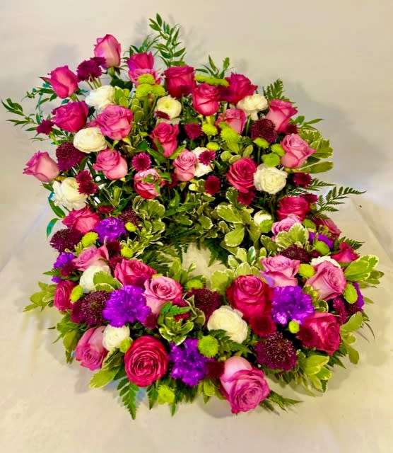 Heart-shaped floral wreath with pink, white, purple, and green blooms