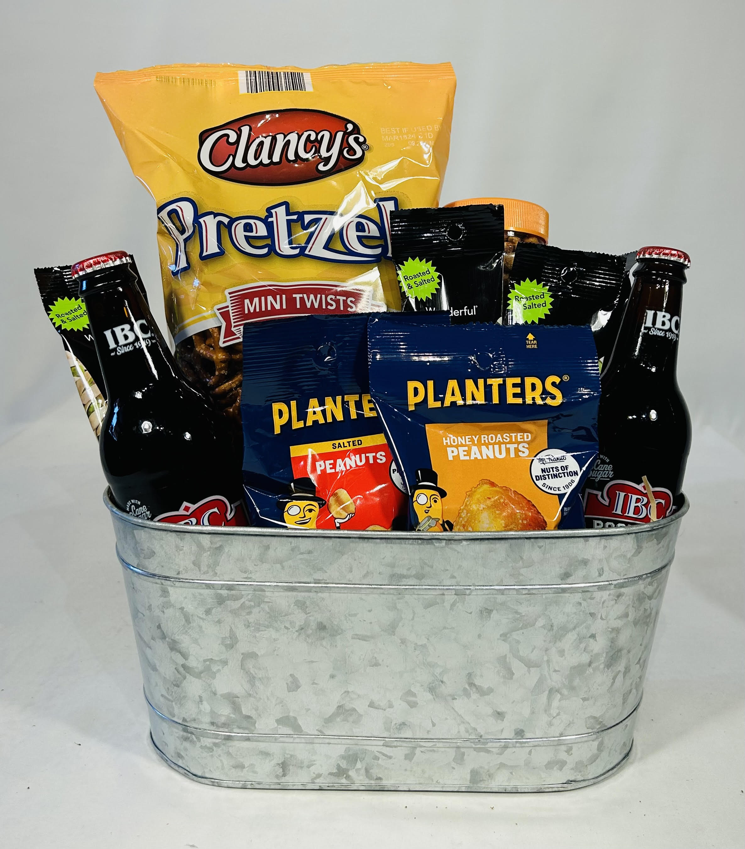 Gift basket with pretzels, peanuts, and bottled drinks in a metal tub