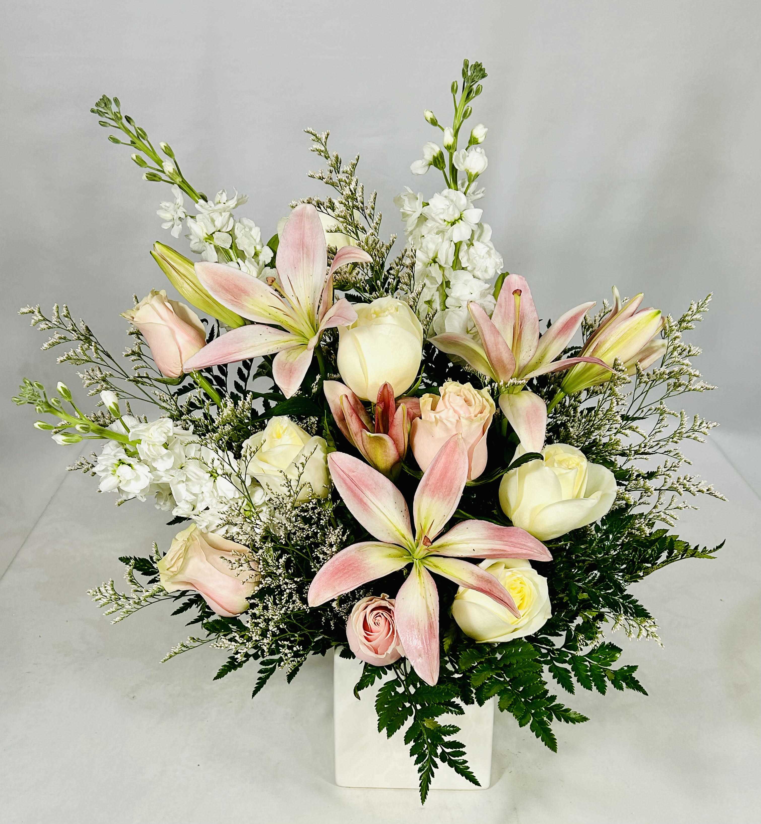 Pink lilies and cream roses in a white vase
