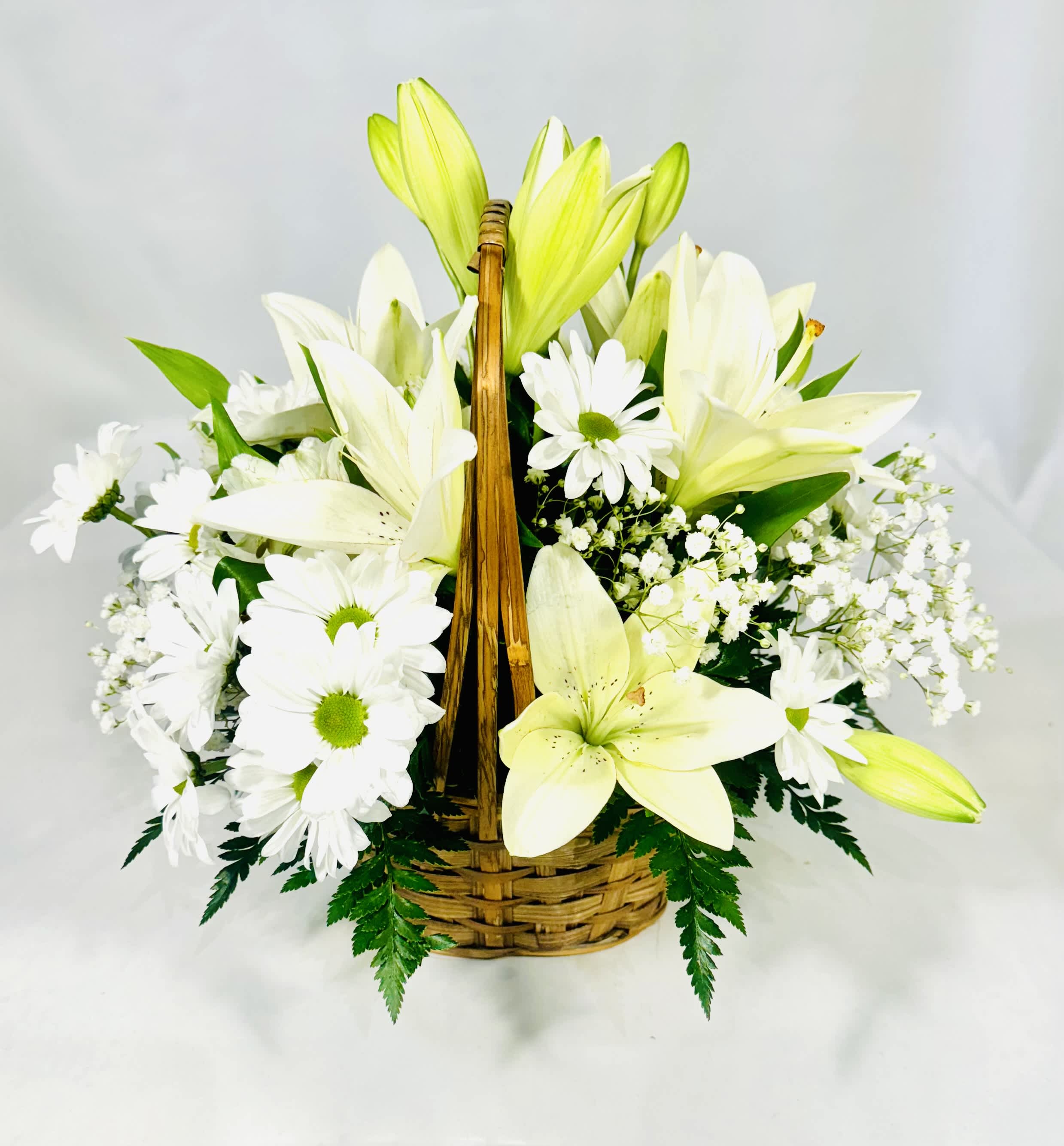 White lilies and daisies arranged in a wicker basket