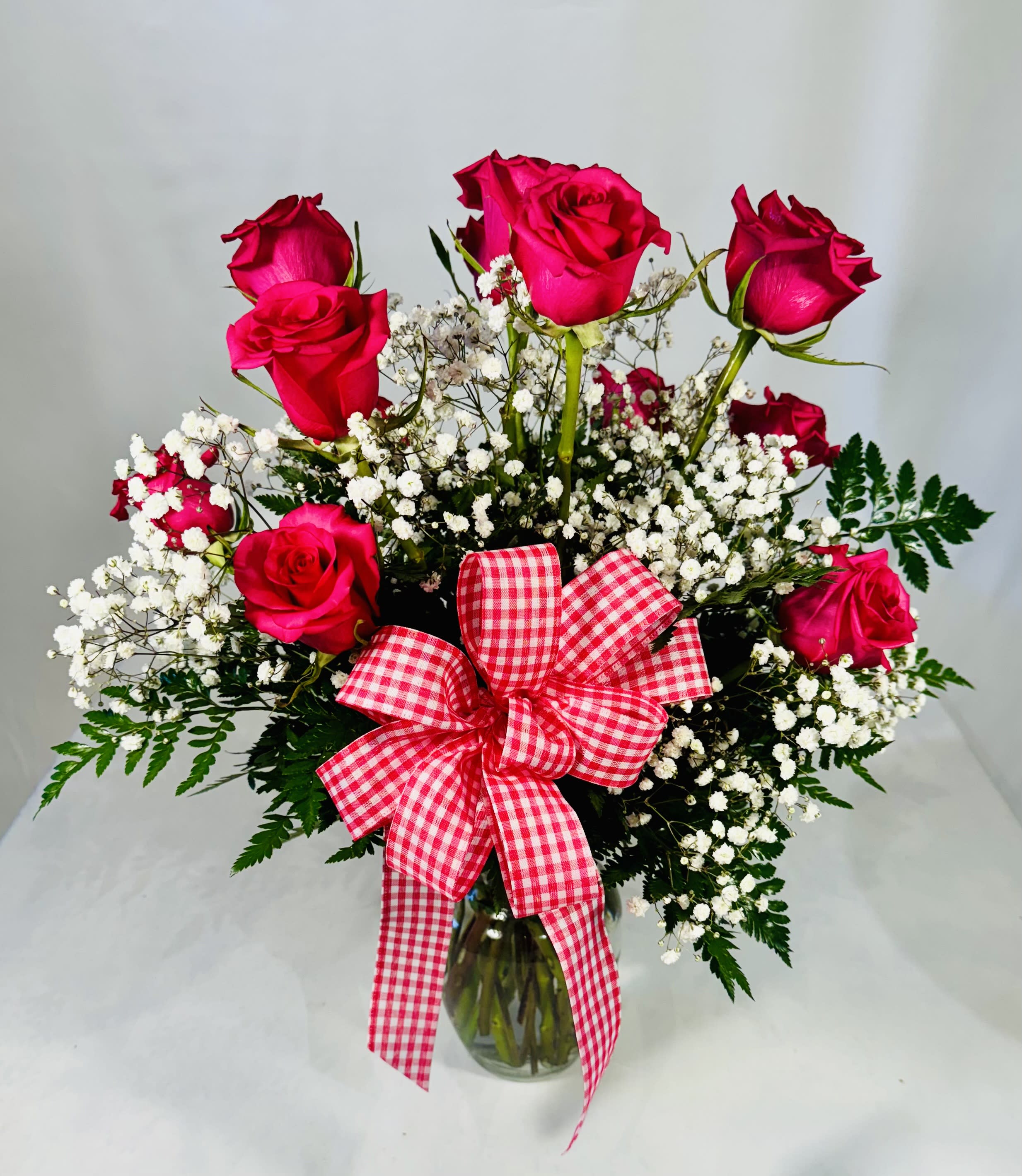 Pink roses with baby's breath in a glass vase and gingham bow