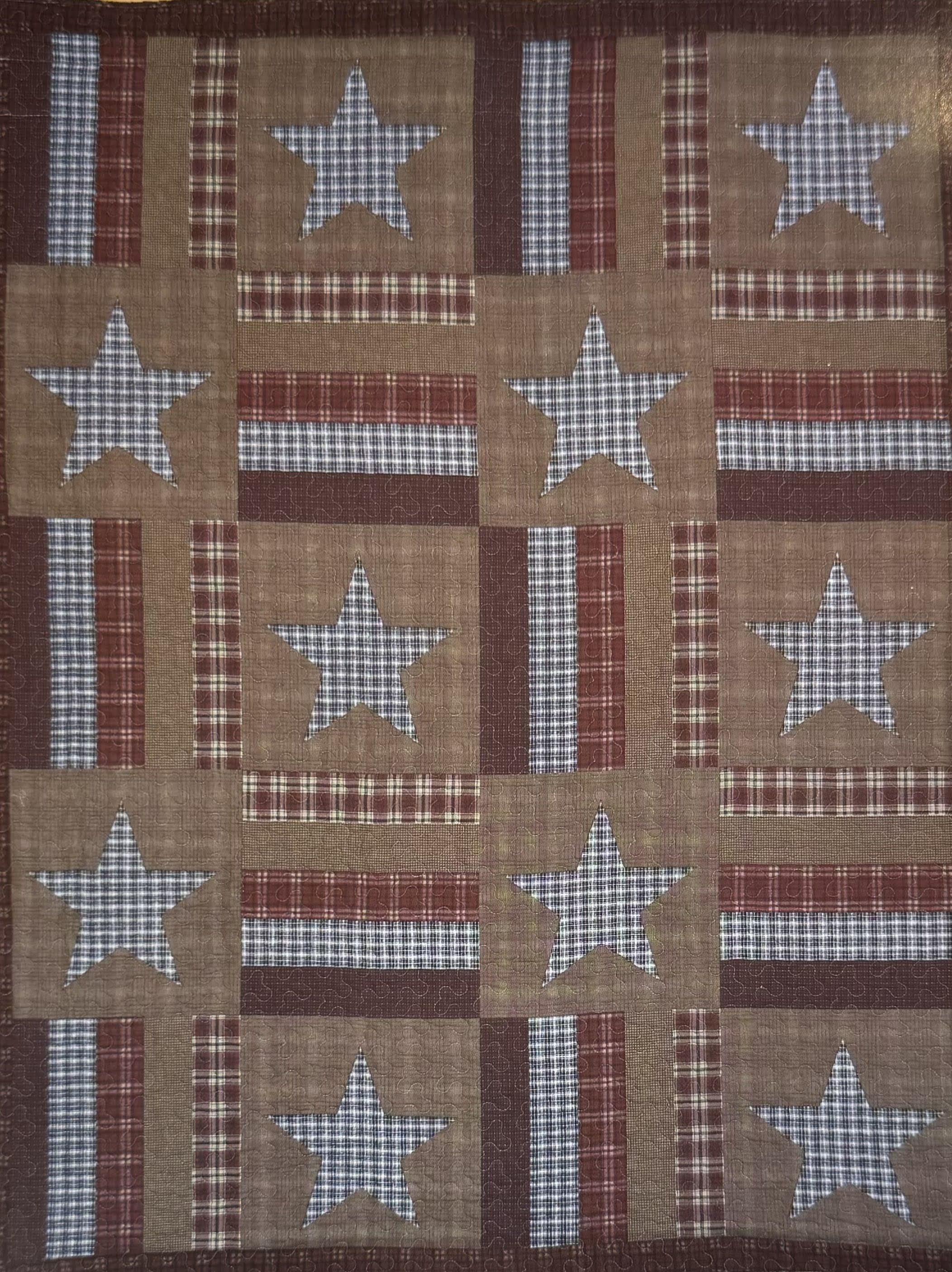 Patchwork quilt with stars and plaid squares in red, tan, and blue