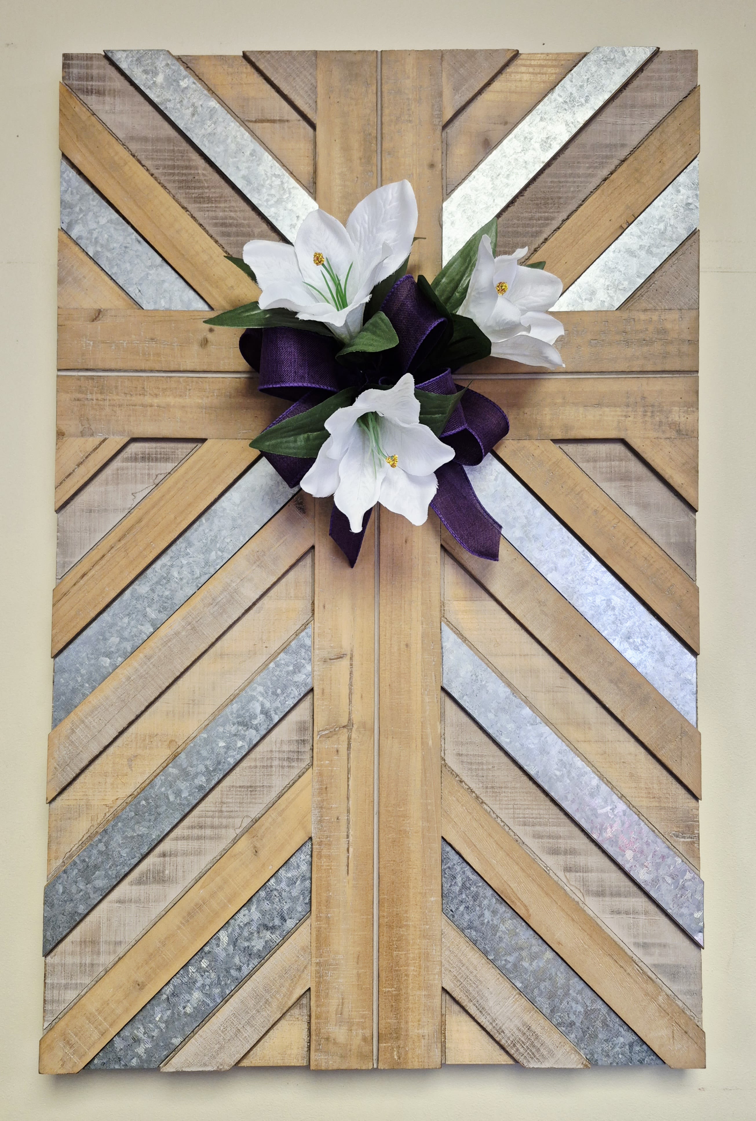White flowers with a purple ribbon on a geometric wood wall hanging