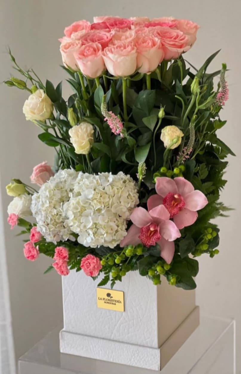 Pink roses, white hydrangea, and pink orchids arranged in a white box