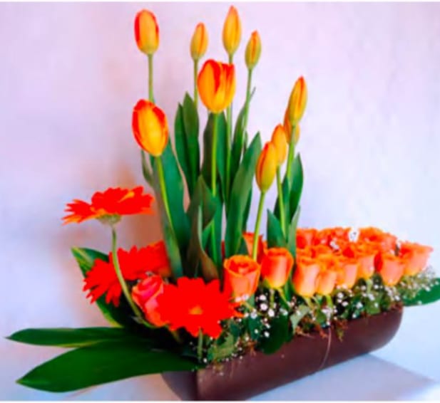 Orange tulips and gerbera daisies arranged in a low brown container