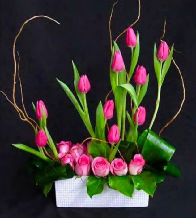 Pink tulips and roses arranged in a white rectangular container