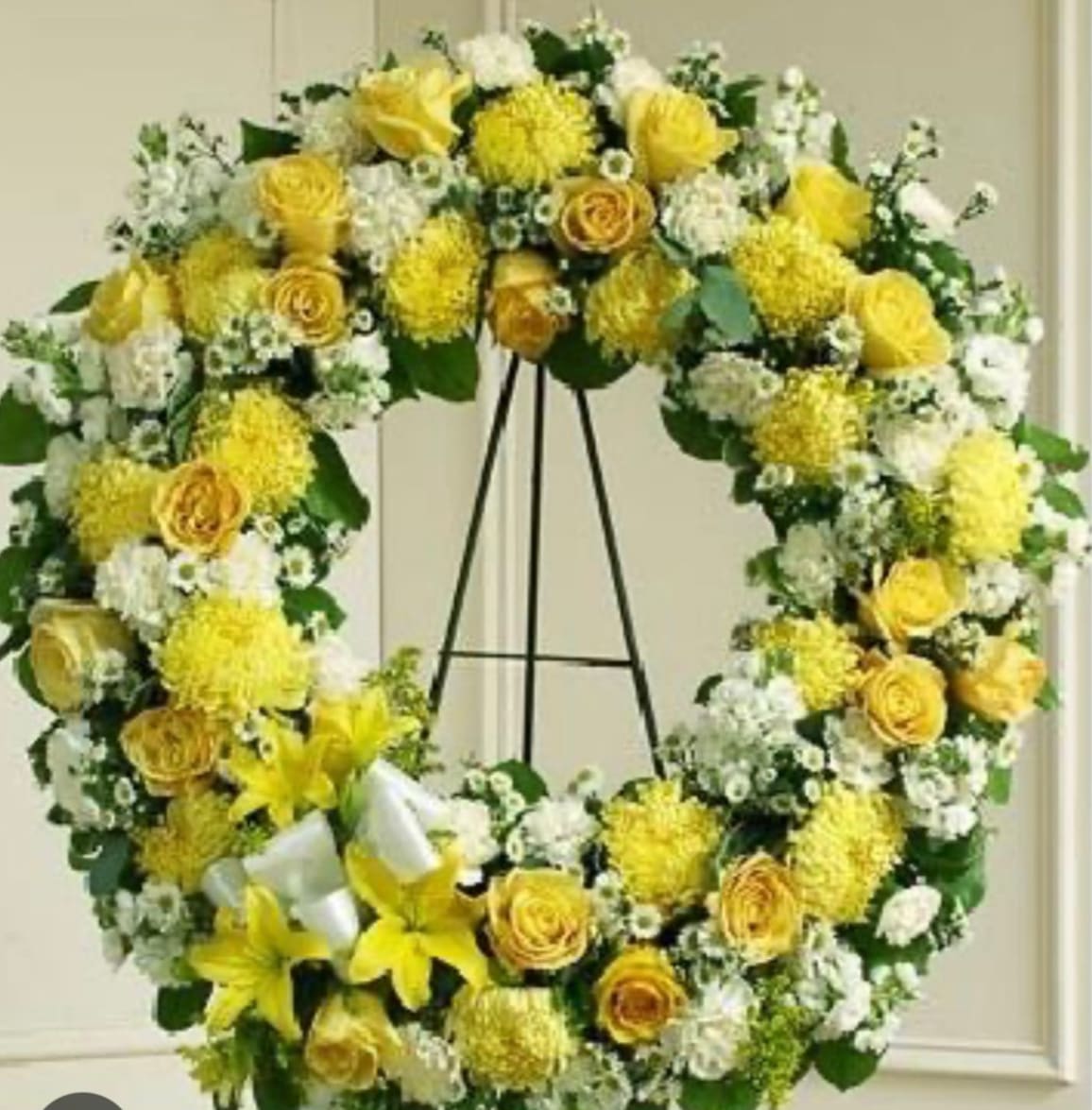 Yellow and white floral wreath on a stand
