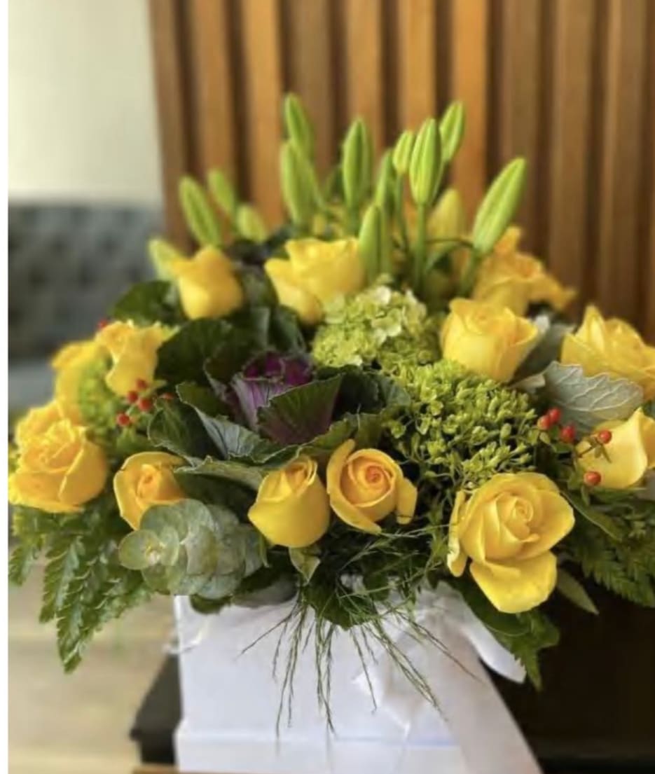 Yellow roses and lilies arranged in a white box