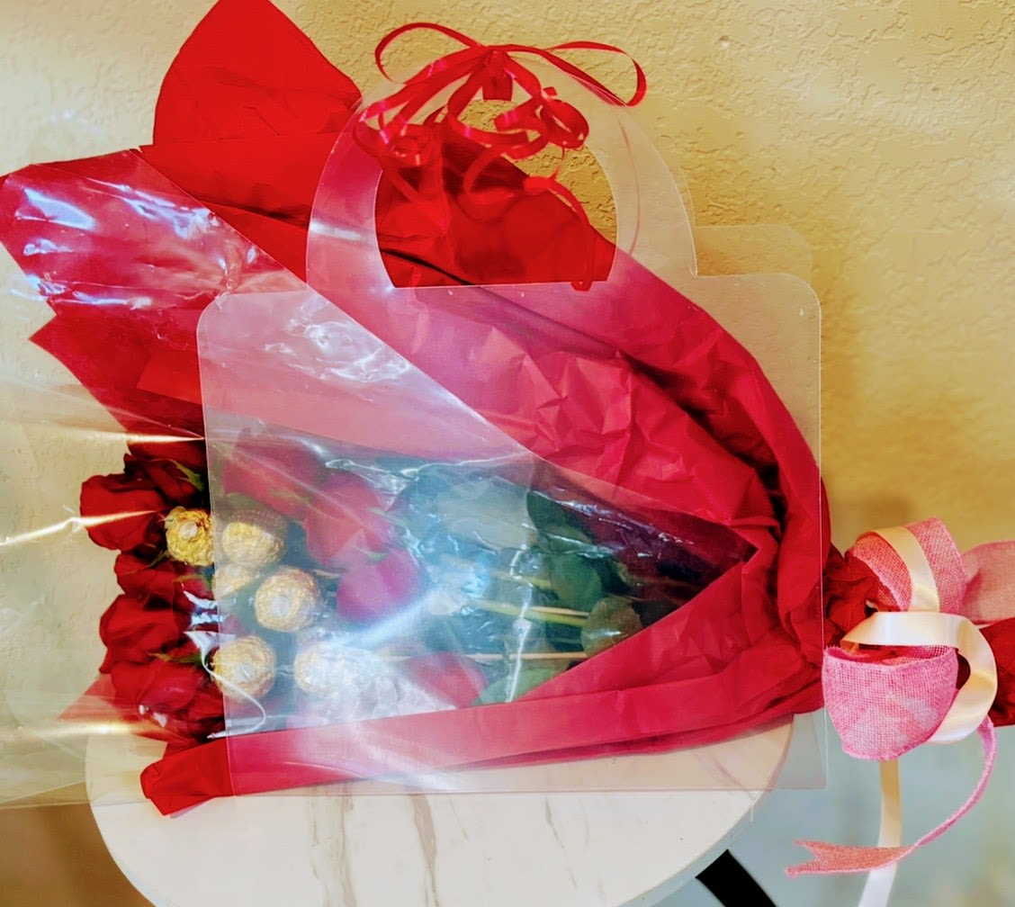 Red rose bouquet wrapped in red and clear plastic with a pink ribbon