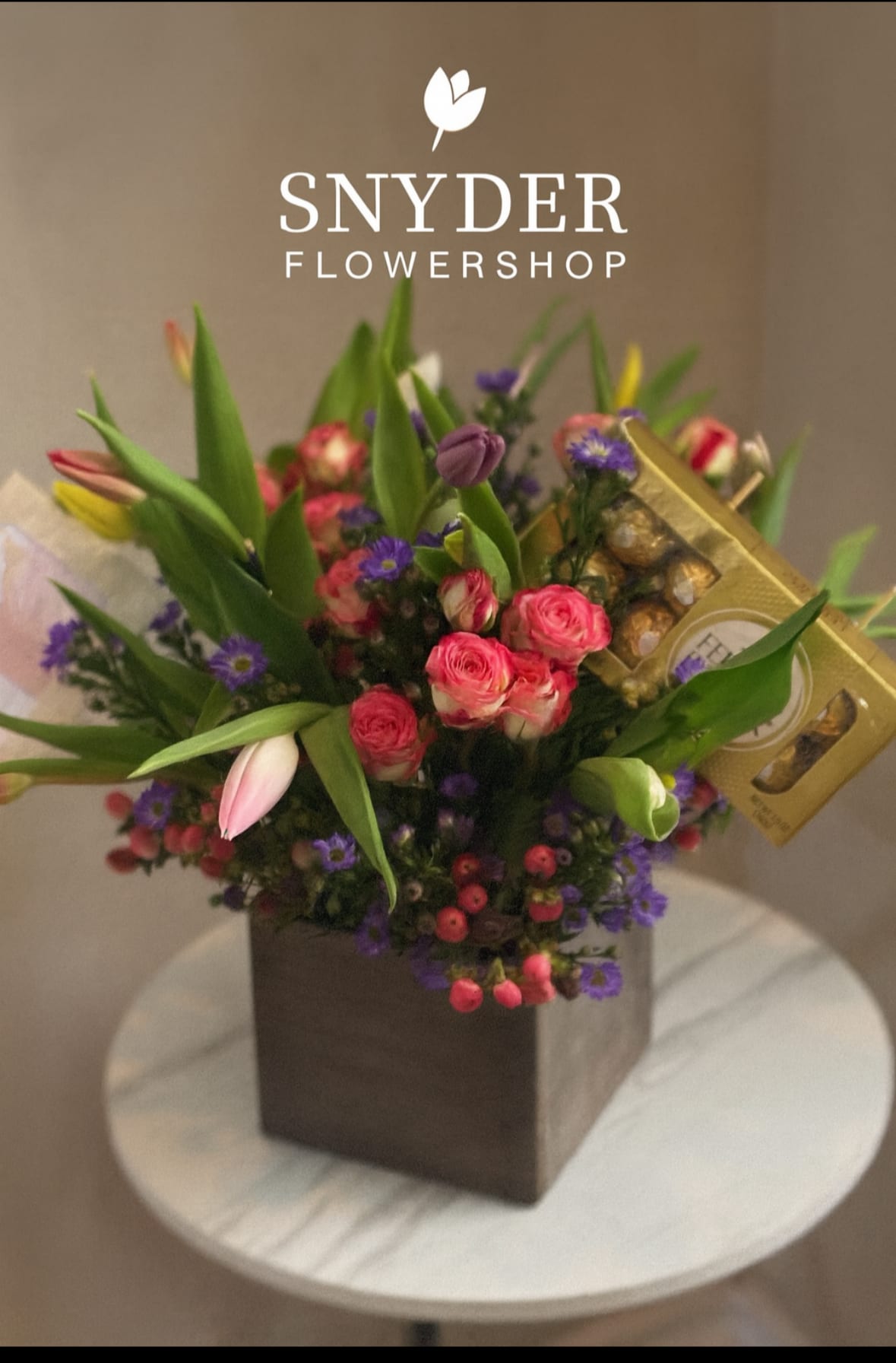 Luxury Tulip &amp; Chocolate Gift Arrangement - A beautiful luxury flower arrangement in San Antonio featuring fresh tulips, spray roses, purple asters, hypericum berries, seasonal blooms, and Ferrero Rocher chocolates designed in an elegant modern container. Handcrafted by Snyder Flowers San Antonio, this floral gift arrangement combines fresh premium flowers with gourmet chocolates for a romantic and unforgettable surprise.   Perfect for birthdays, anniversaries, Mother’s Day, romantic gifts, thank you gifts, or special celebrations.  We proudly offer same-day flower delivery in San Antonio with fresh high-quality flowers and exceptional customer service.  Elegant floral designs created with premium blooms, modern garden style, and luxury gift presentation.  Serving Stone Oak, Medical Center, Alamo Heights, Cibolo, Universal City, Live Oak, Helotes, Castle Hills, Shavano Park, and Downtown San Antonio.  Looking for a trusted florist in San Antonio, same day flower delivery, or flowers and chocolates near you? Snyder Flowers specializes in elegant handcrafted floral gifts designed to impress and delivered fresh the same day.
