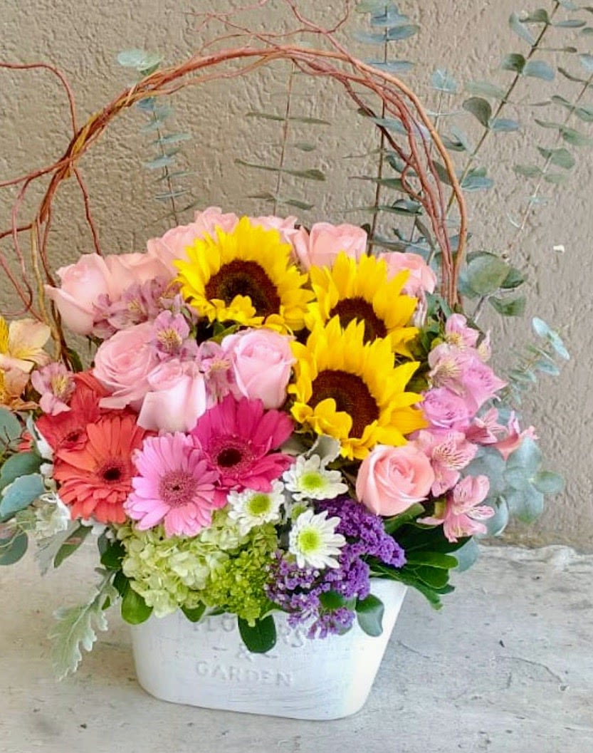 Sunflower &amp; Pink Garden Arrangement - A bright and cheerful flower arrangement in San Antonio featuring fresh sunflowers, pink roses, gerbera daisies, hydrangeas, alstroemeria, chrysanthemums, statice, and seasonal greenery beautifully designed in a charming garden-style container. Handcrafted by Snyder Flowers San Antonio, this colorful floral arrangement brings joy, elegance, and fresh spring beauty to any occasion.   Perfect for birthdays, Mother’s Day, celebrations, get well wishes, thank you gifts, or everyday surprises.  We proudly offer same-day flower delivery in San Antonio with fresh premium flowers and exceptional customer service.  Luxury floral designs created with high-quality blooms, vibrant colors, and elegant garden-inspired style.  Serving Stone Oak, Medical Center, Alamo Heights, Cibolo, Universal City, Live Oak, Helotes, Castle Hills, Shavano Park, and Downtown San Antonio.  Looking for a trusted florist in San Antonio, same day flower delivery, or sunflower arrangements near you? Snyder Flowers creates beautiful handcrafted floral designs delivered fresh for every special moment.