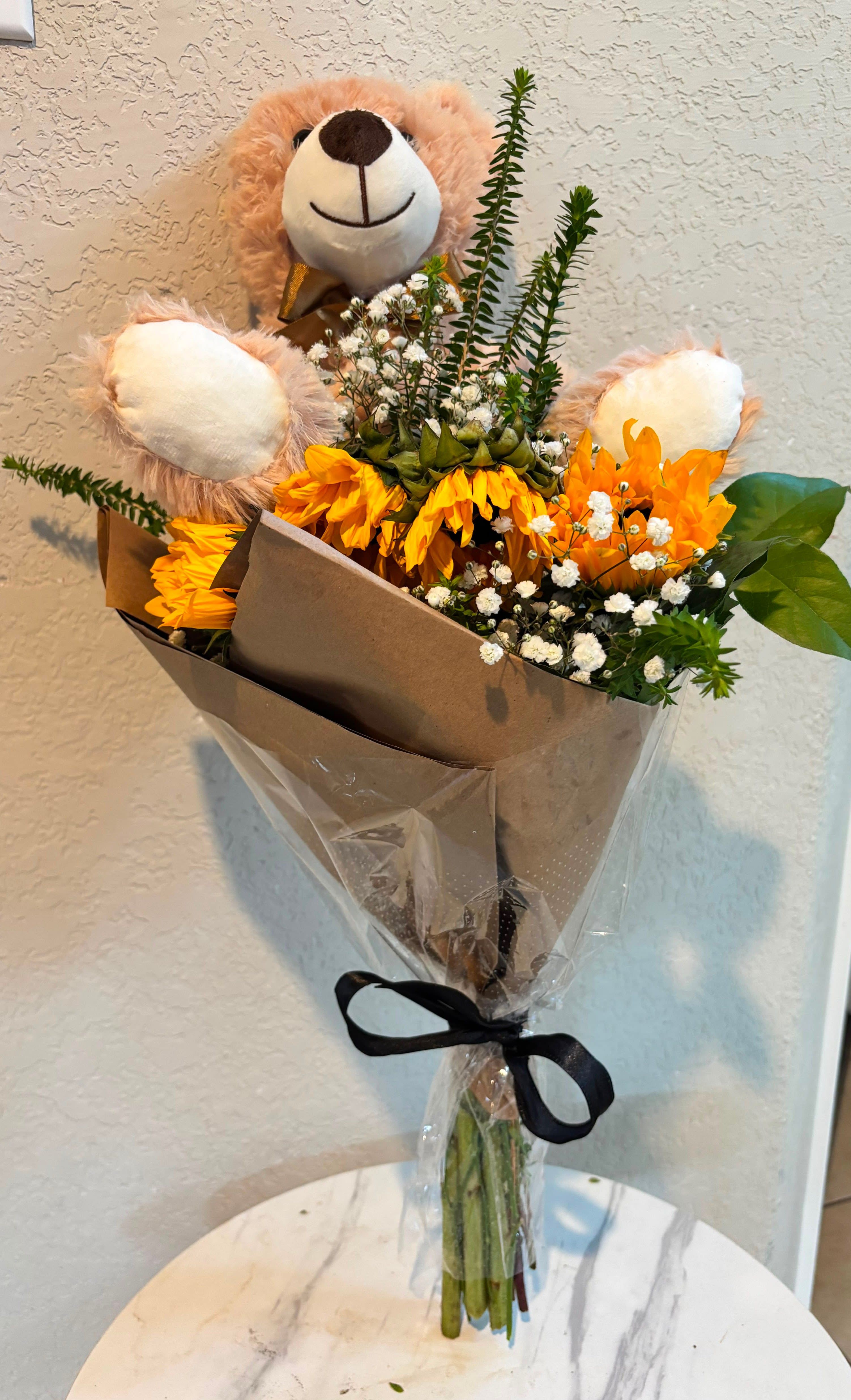 Golden Sunshine Teddy Bouquet - Brighten someone's day with our Golden Sunshine Teddy Bouquet, a cheerful handcrafted floral gift featuring vibrant sunflowers, delicate baby's breath, lush greenery, and an adorable teddy bear. Designed by Snyder Flowers in San Antonio, Texas, this arrangement is perfect for birthdays, get well wishes, congratulations, new baby celebrations, thinking of you gifts, thank you flowers, friendship gifts, anniversaries, graduation gifts, and everyday surprises. Our flower shop proudly offers same-day flower delivery throughout Stone Oak, Alamo Heights, The Dominion, Shavano Park, Medical Center, Helotes, Schertz, Cibolo, Boerne, Bulverde, and surrounding San Antonio communities. This unique sunflower bouquet combines warmth, happiness, and affection, making it one of the most popular flower gifts for any special occasion.