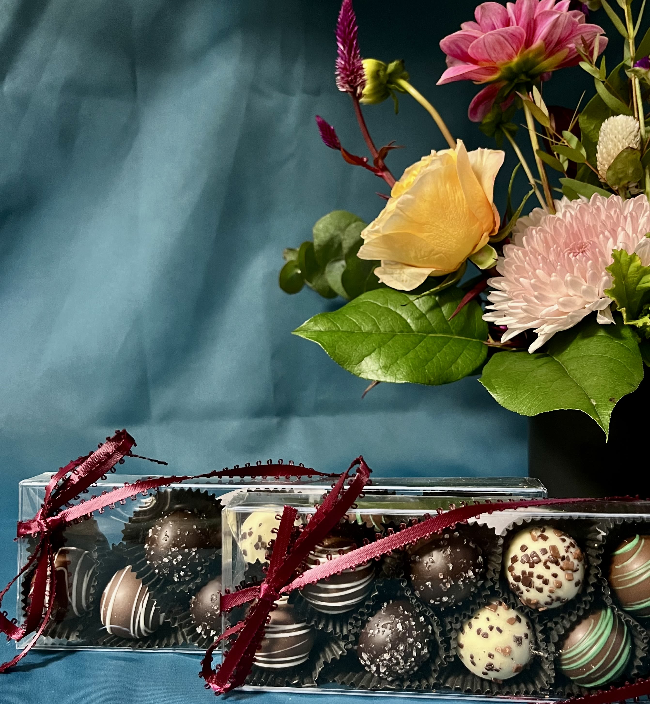 Gift set with mixed flower arrangement in a black vase and two boxes of assorted chocolate truffles