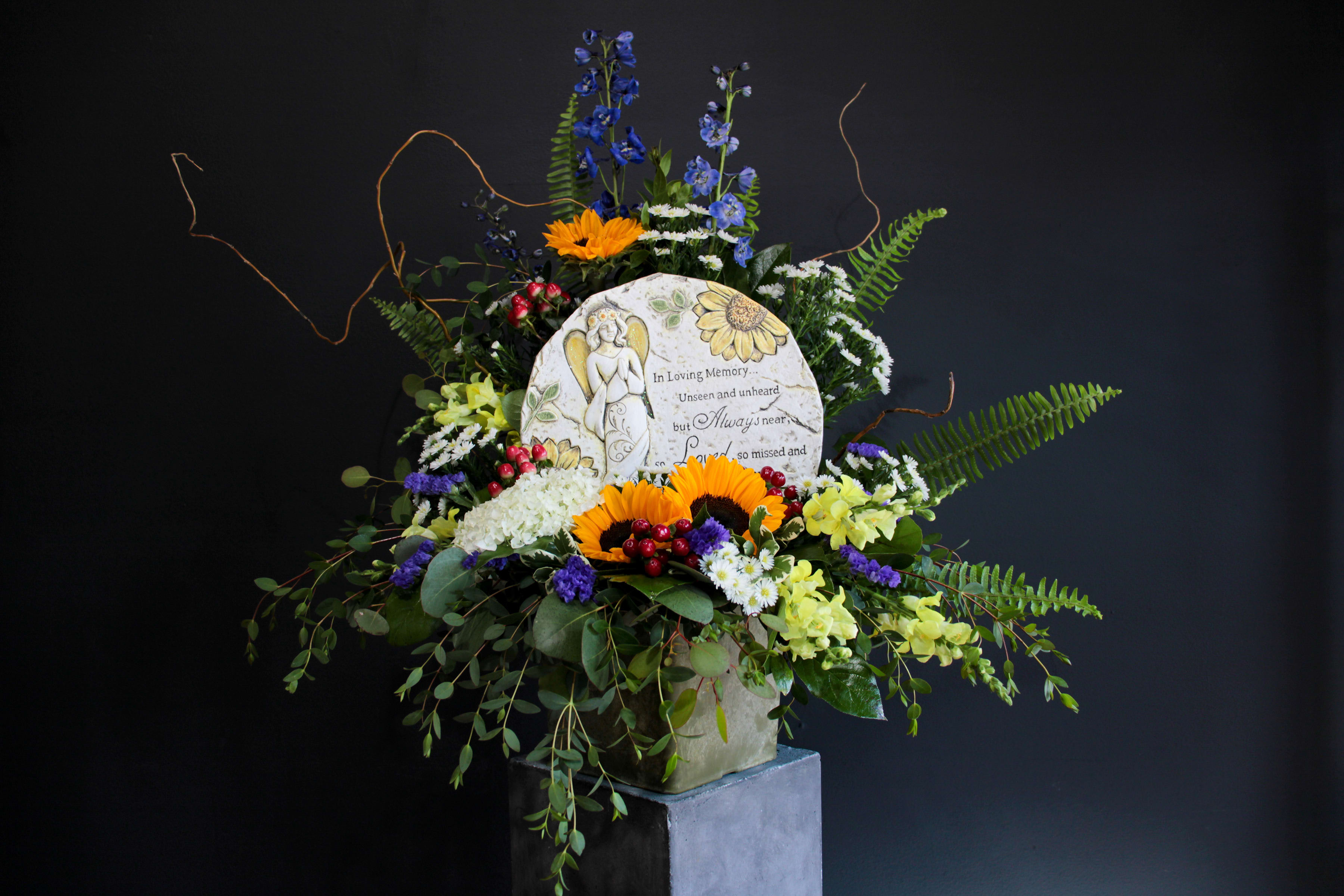 Sympathy floral arrangement with a memorial plaque and mixed flowers