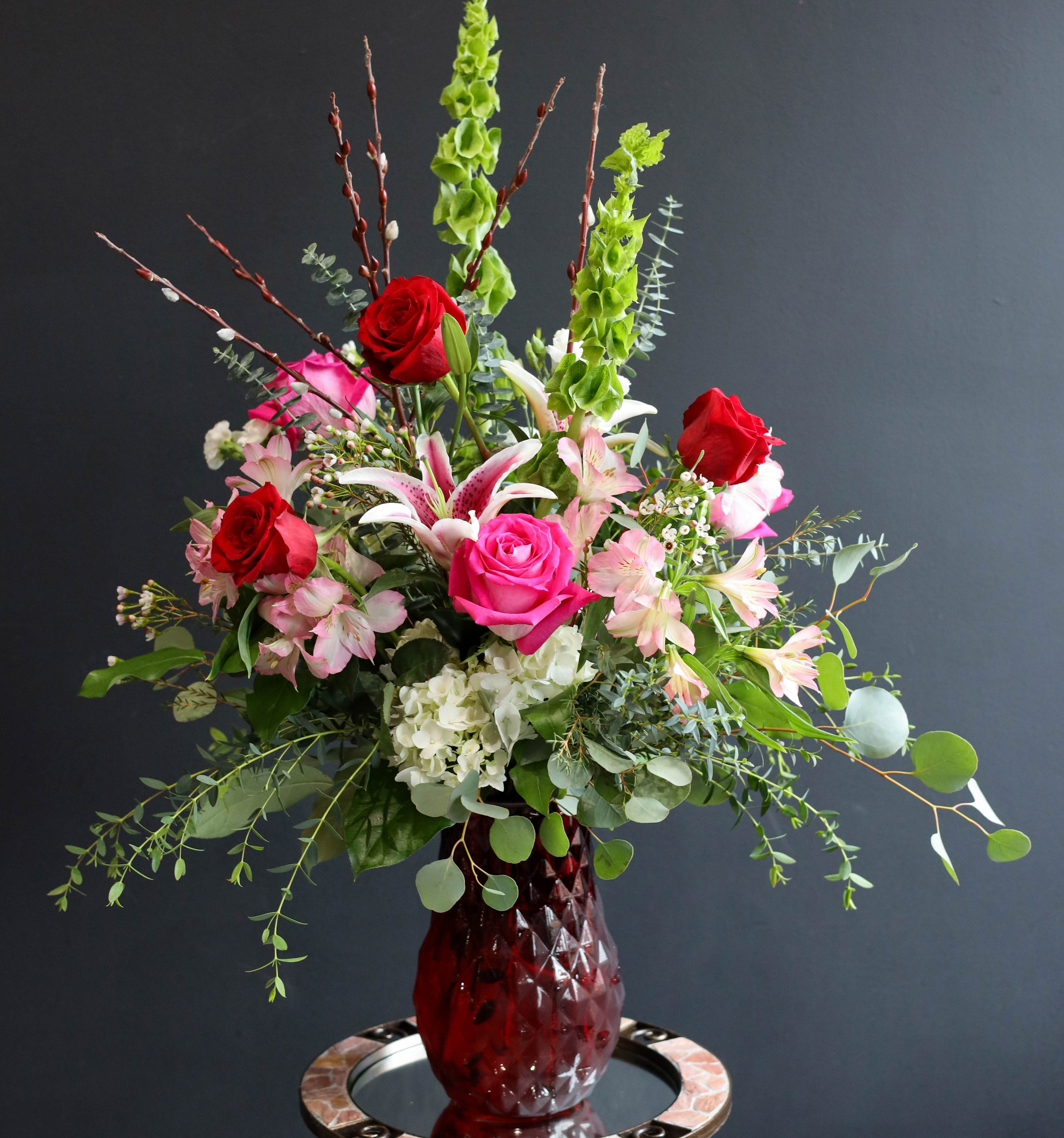 Awestruck - A lush airy arrangement filled with Roses, Lilies, Alstroemeria, Bells of Ireland, in a ruby red vase which will leave any recipient completely awestruck this Valentine's Day!