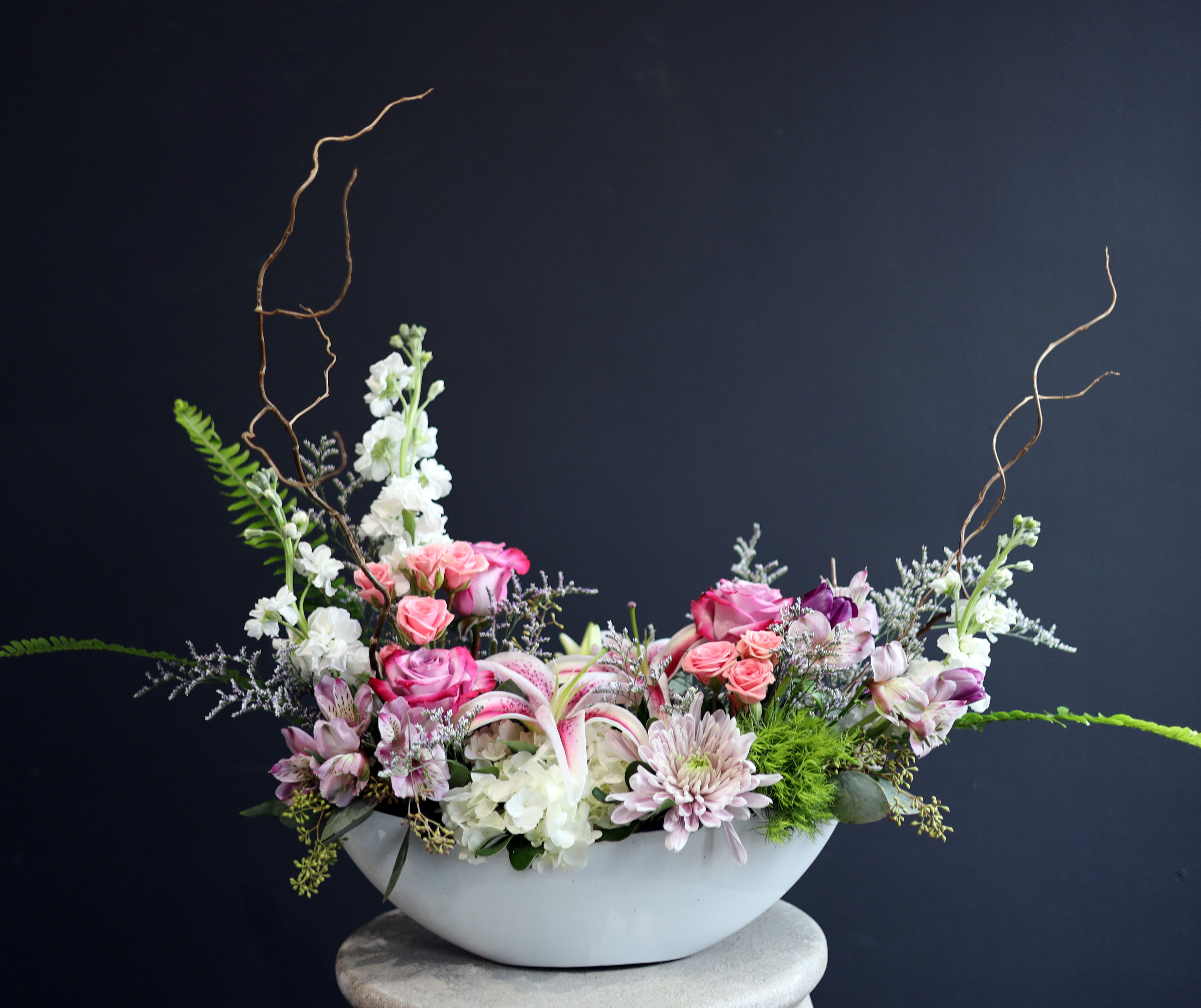 Pink and white floral arrangement in a white bowl vase