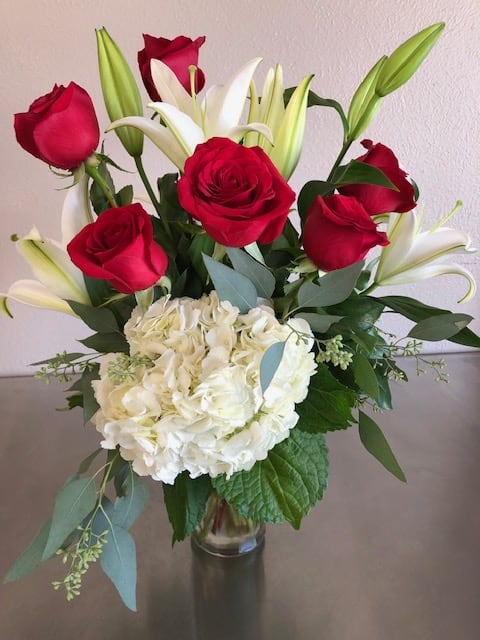 Bouquet of red roses and white lilies with white hydrangea in a glass vase