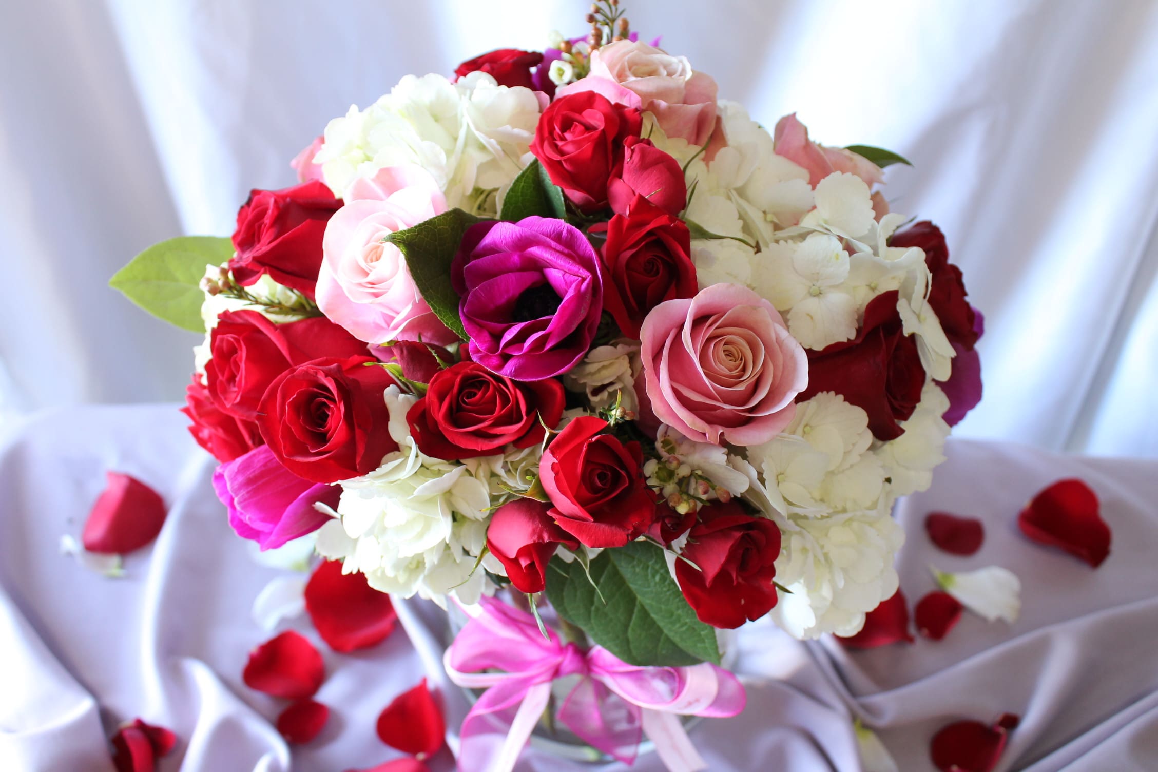 Bouquet of red, pink, and white roses with a pink ribbon