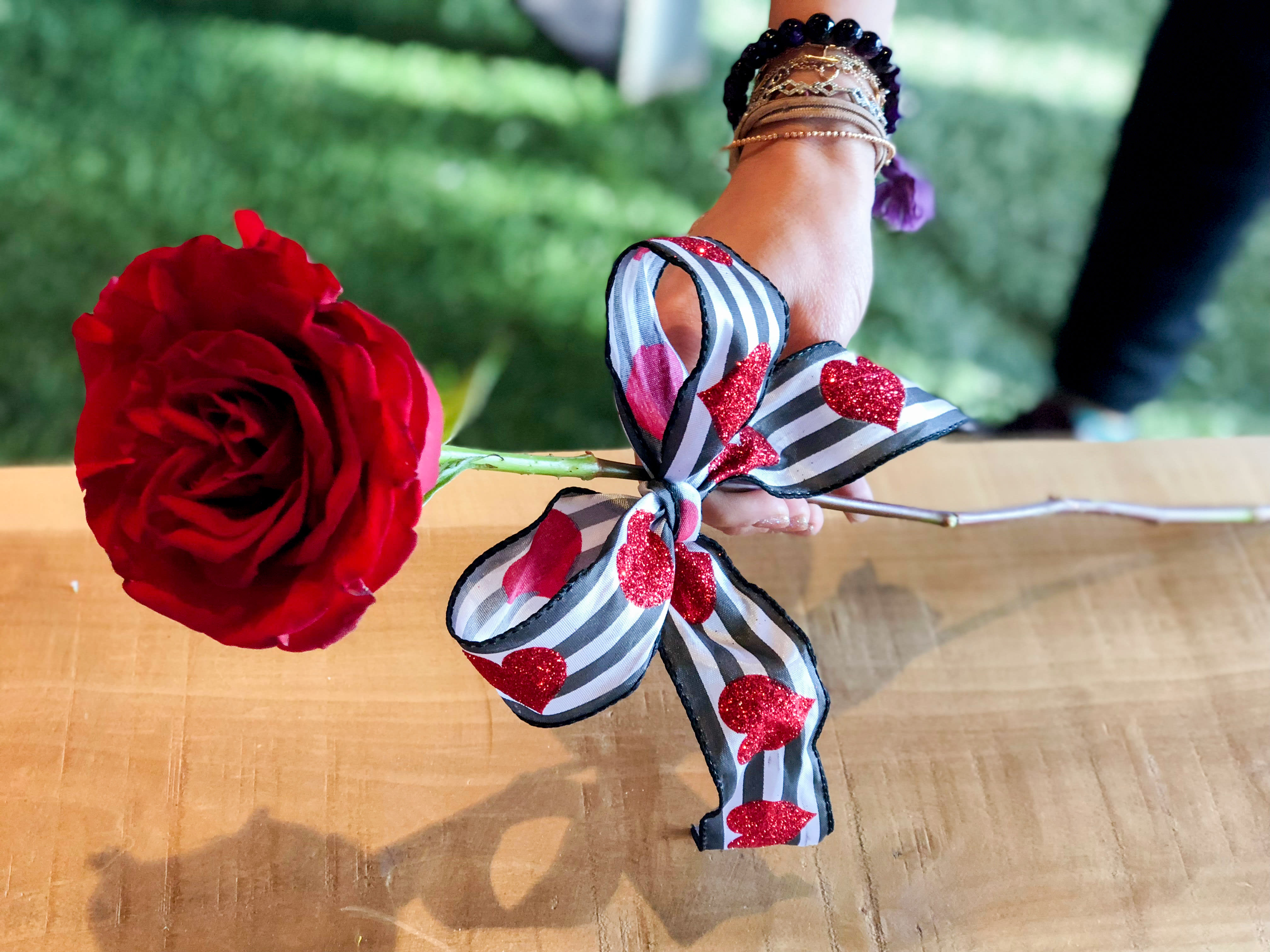 Single red rose with a striped heart ribbon bow