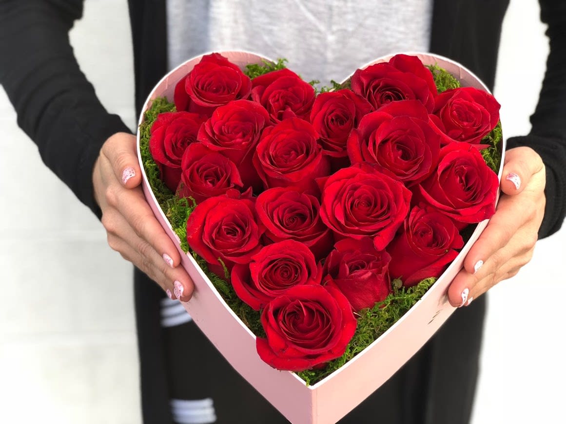Heart-shaped box of red roses held in two hands